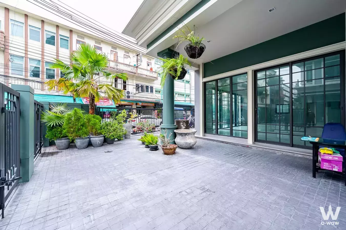 Front courtyard of Tiger Lane Sansiri featuring black grid sliding doors and hanging ferns in wire baskets