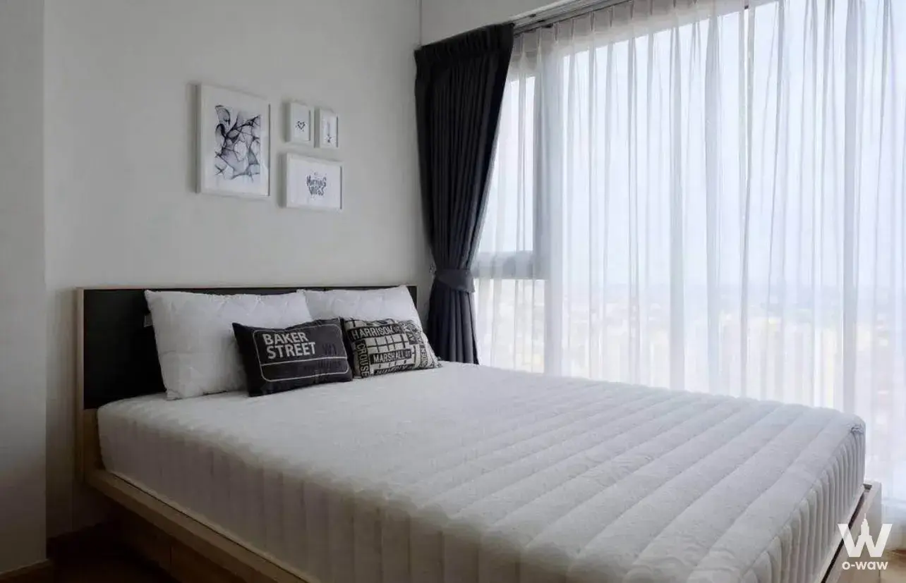 Bedroom in Whizdom Connect Sukhumvit showing a queen bed, framed art, and floor-to-ceiling windows with city views