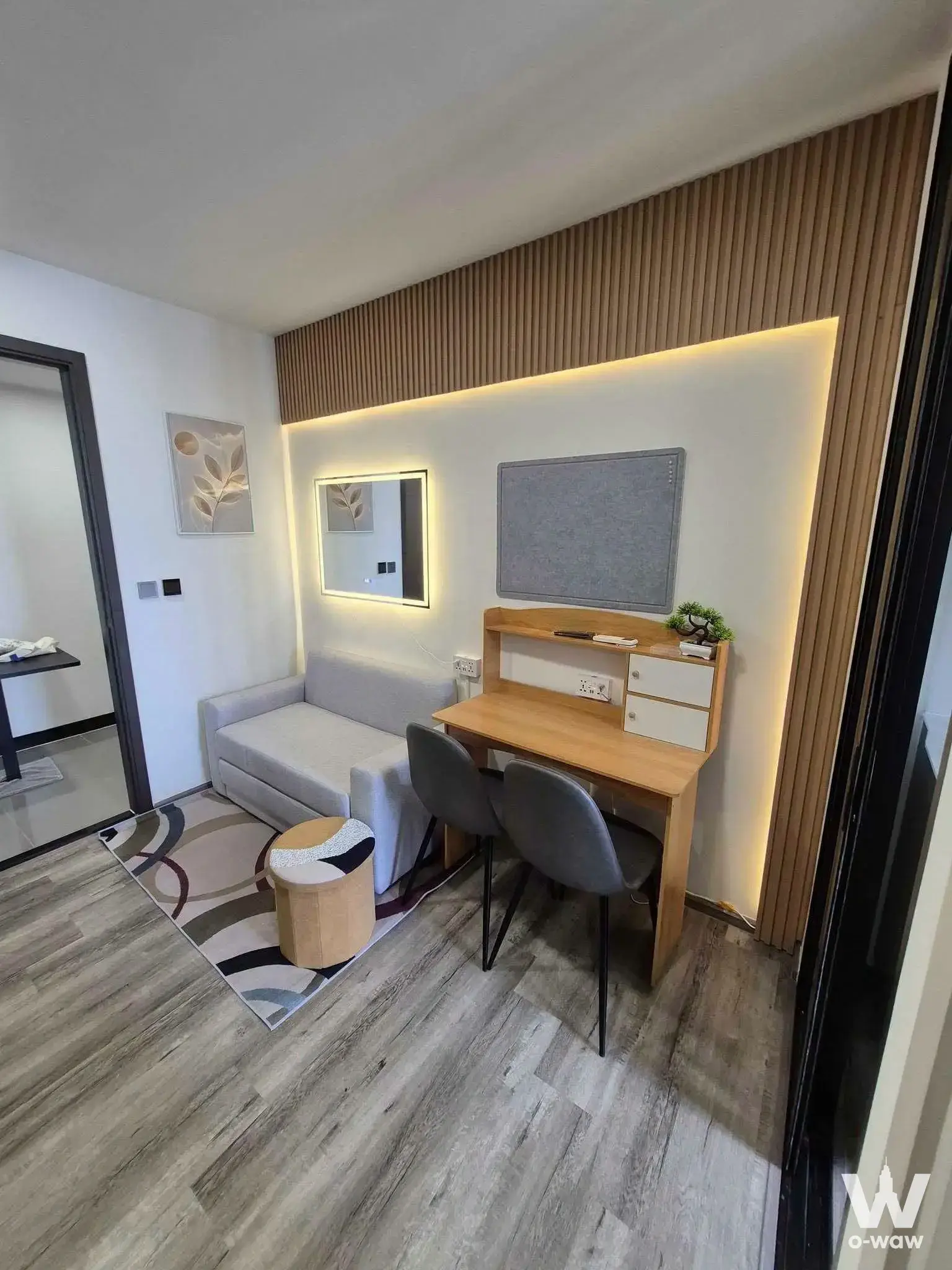 Studio living area with wood-slat feature wall and backlit mirror in a 1-bed condo for rent at Modiz Vault Kaset Sripatum