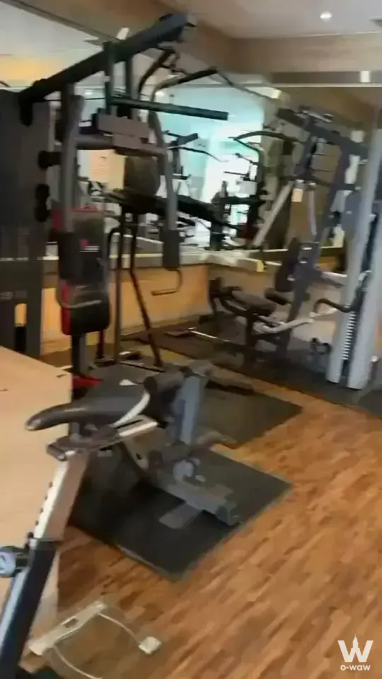 Rowing machine and cable crossover station fill the indoor gym of this 2-bed condo for rent in Witthayu Complex