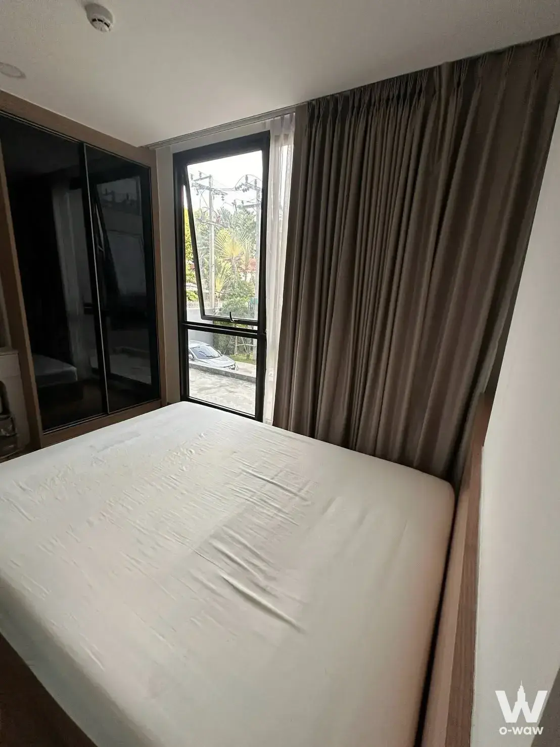 Modern 1-bed condo bedroom in Cybiq Rama IX with black glass wardrobe and street view