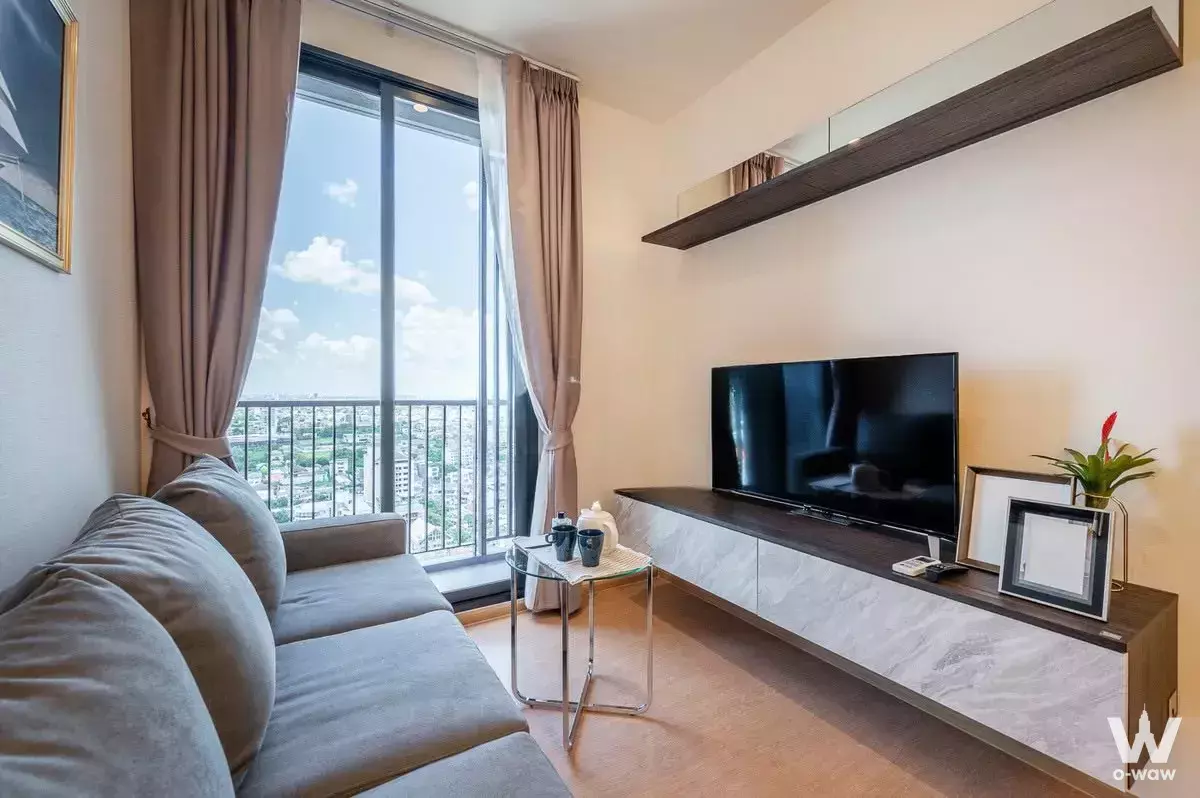 Bright living room in MARU Ekkamai 2 condo featuring city views through sliding glass doors