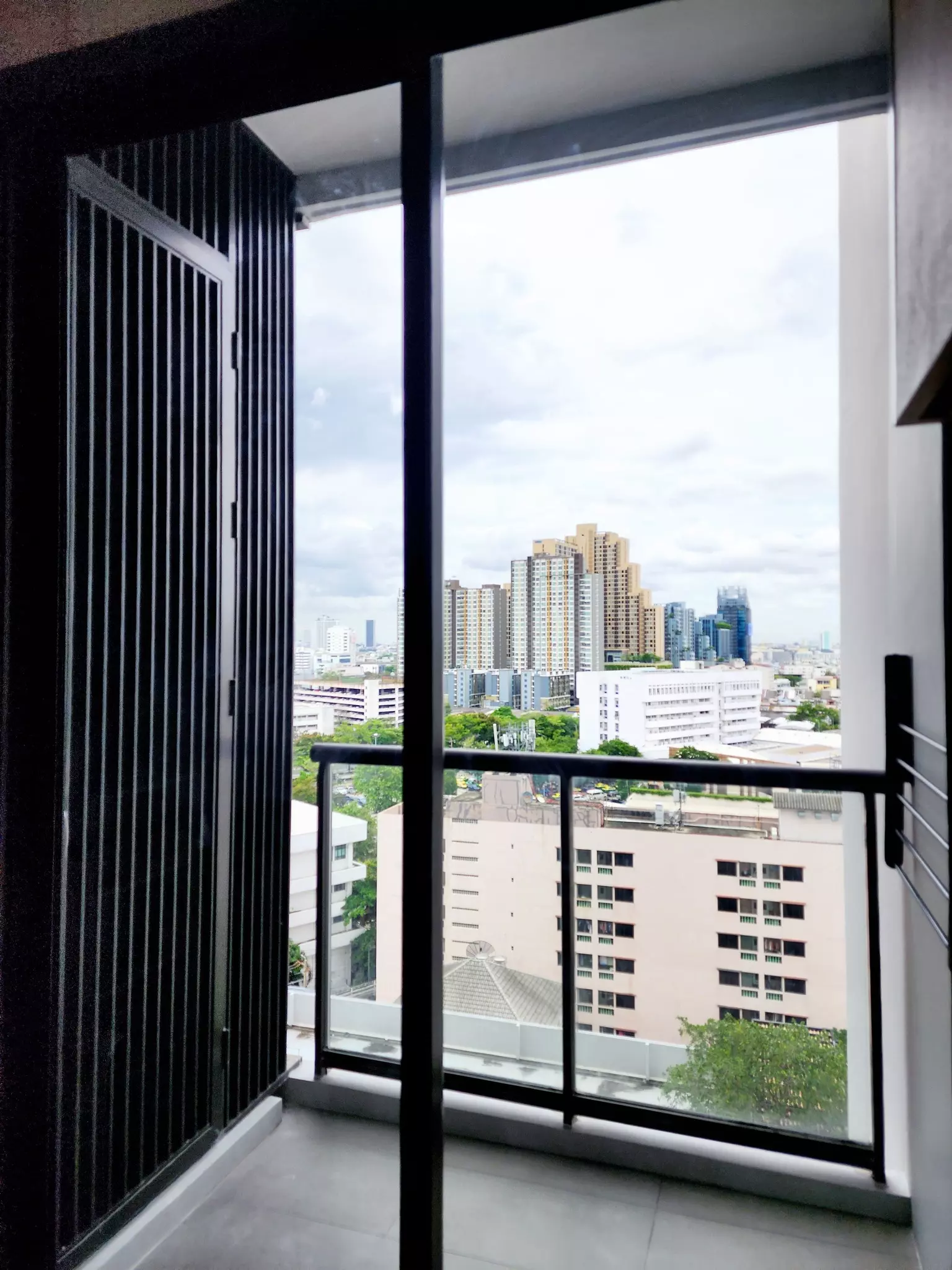Spacious balcony with black metal frames and city skyline view in M Jatujak 1-bed condo
