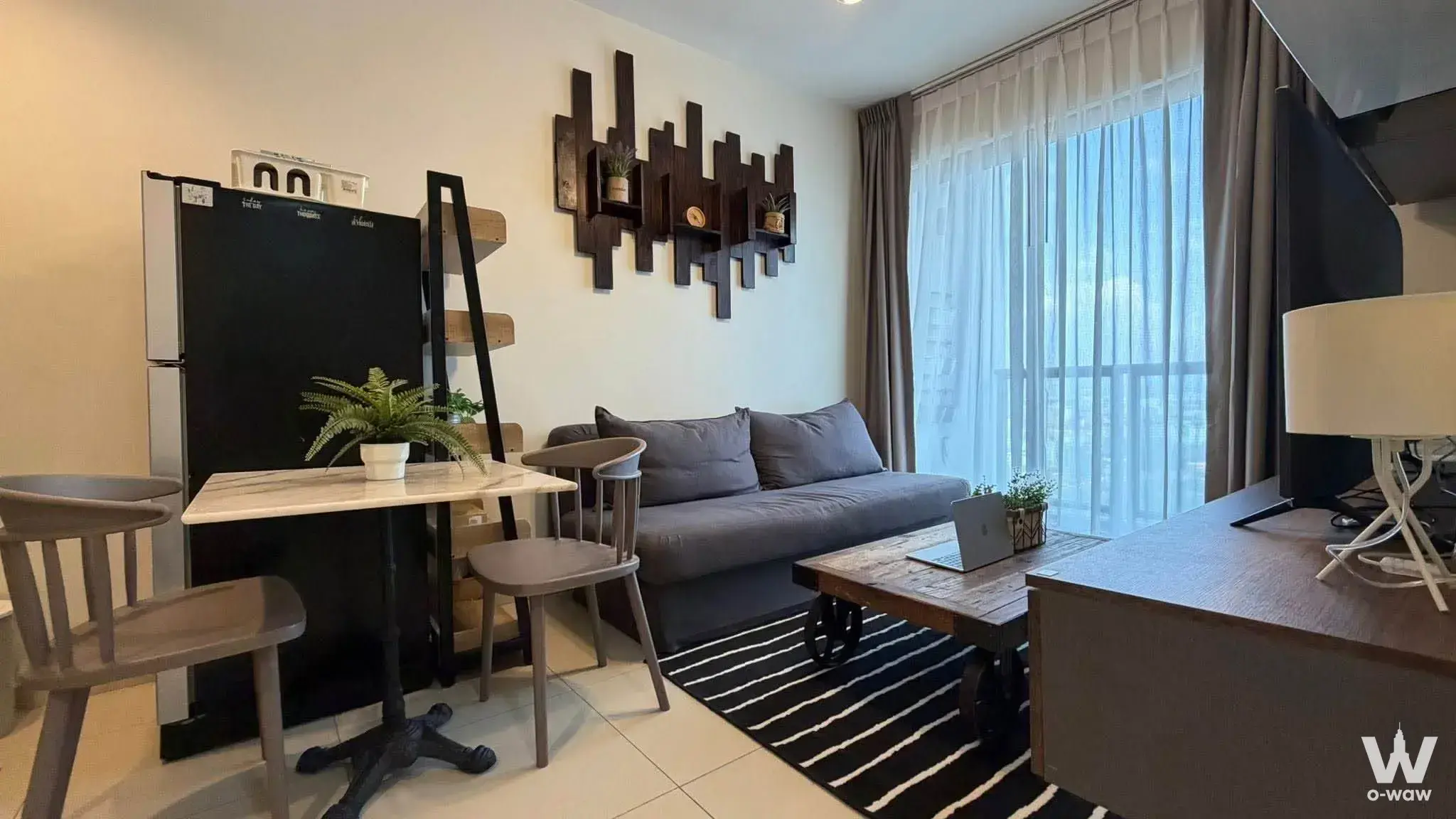Open-plan living area in a Unixx South Pattaya 1-bed condo with a grey sofa, reclaimed-wood coffee table, and city-view