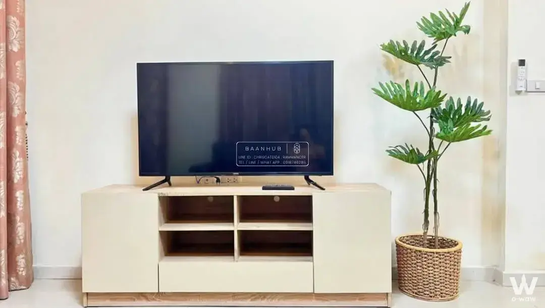 Living room with large TV and cream media console in 3-bed townhouse for rent in Bangkok