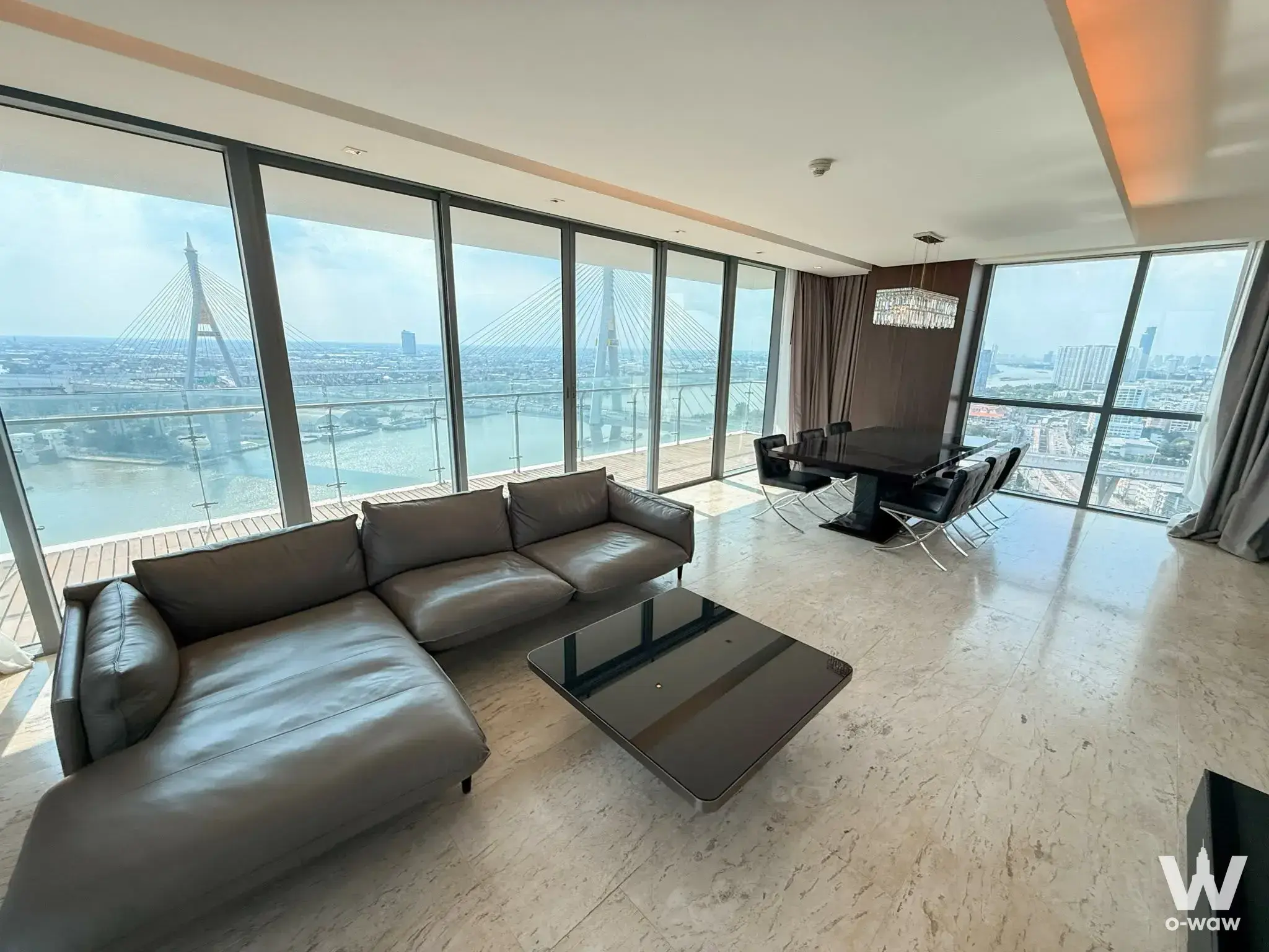 River view from The Pano 3-bed condo living room with grey sectional sofa and floor-to-ceiling windows