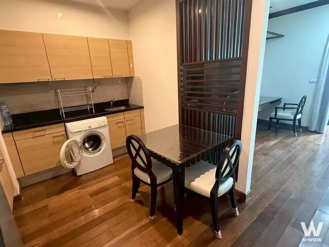 Kitchen dining area in The Address Chidlom with black granite counters and a dark wood slat room divider