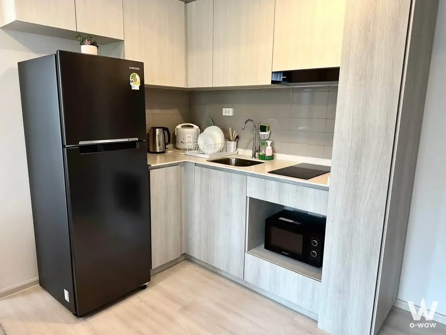 Fully equipped kitchen in a 1-bed condo for rent in COBE Ratchada-Rama 9 with light wood cabinets and white quartz countertop