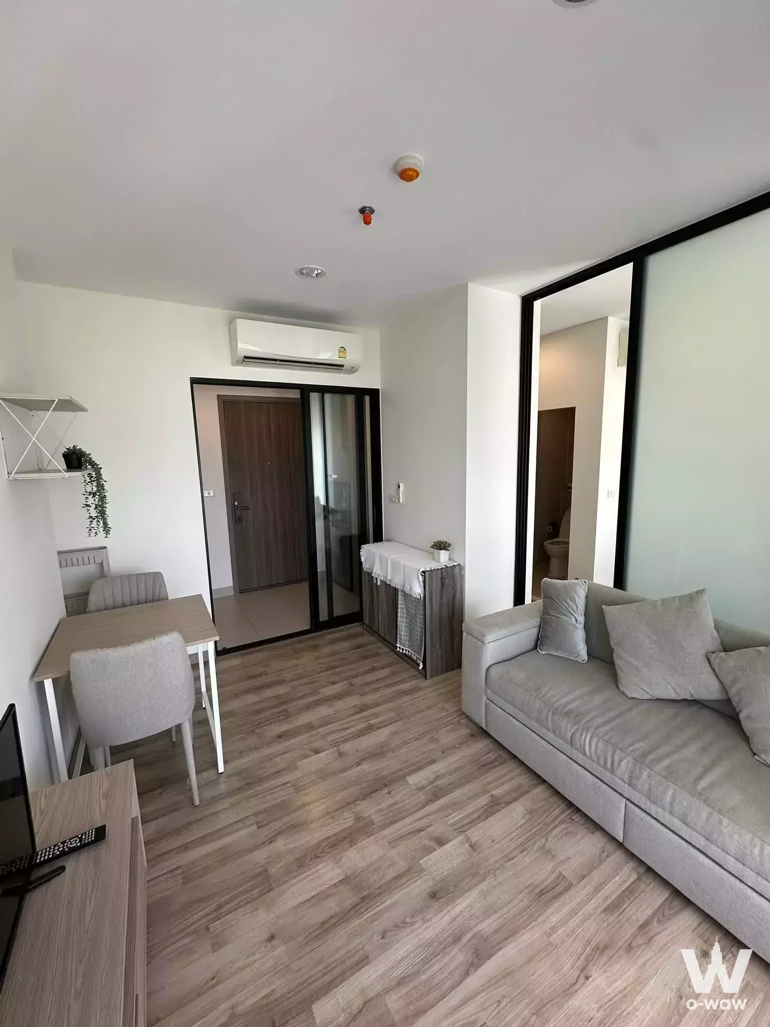 Niche MONO Charoen Nakhon living room with grey sofa, dining nook, and minimalist neutral decor