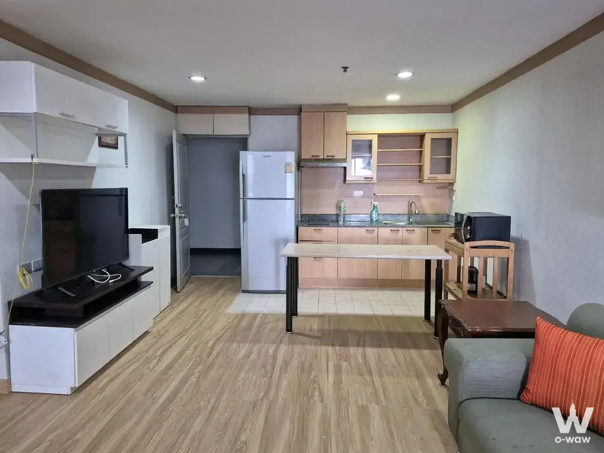 Open-plan living kitchen in Diamond Sukhumvit rental with light wood floors and grey sofa