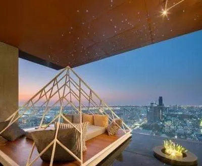 Rooftop terrace lounge with wooden deck and geometric frame overlooking the Bangkok skyline at dusk