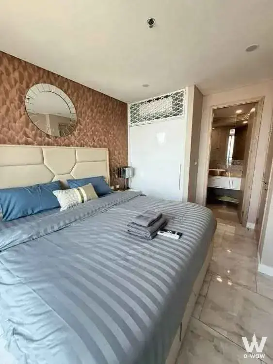 Bedroom with hexagonal headboard and en-suite bathroom in a 1-bed condo for sale at Copacabana Beach Jomtien