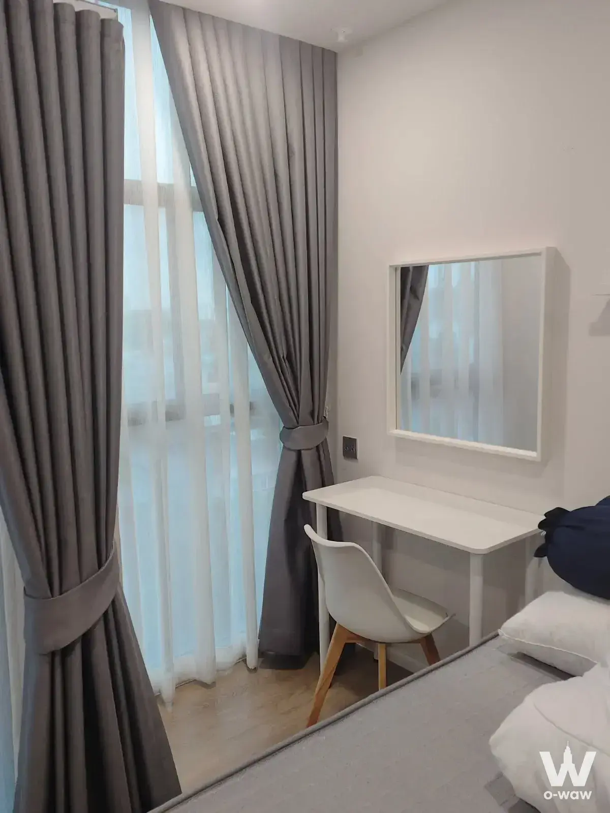 Bright bedroom corner in Ivory Ratchada 32 featuring a white desk, mirror, and floor-to-ceiling windows