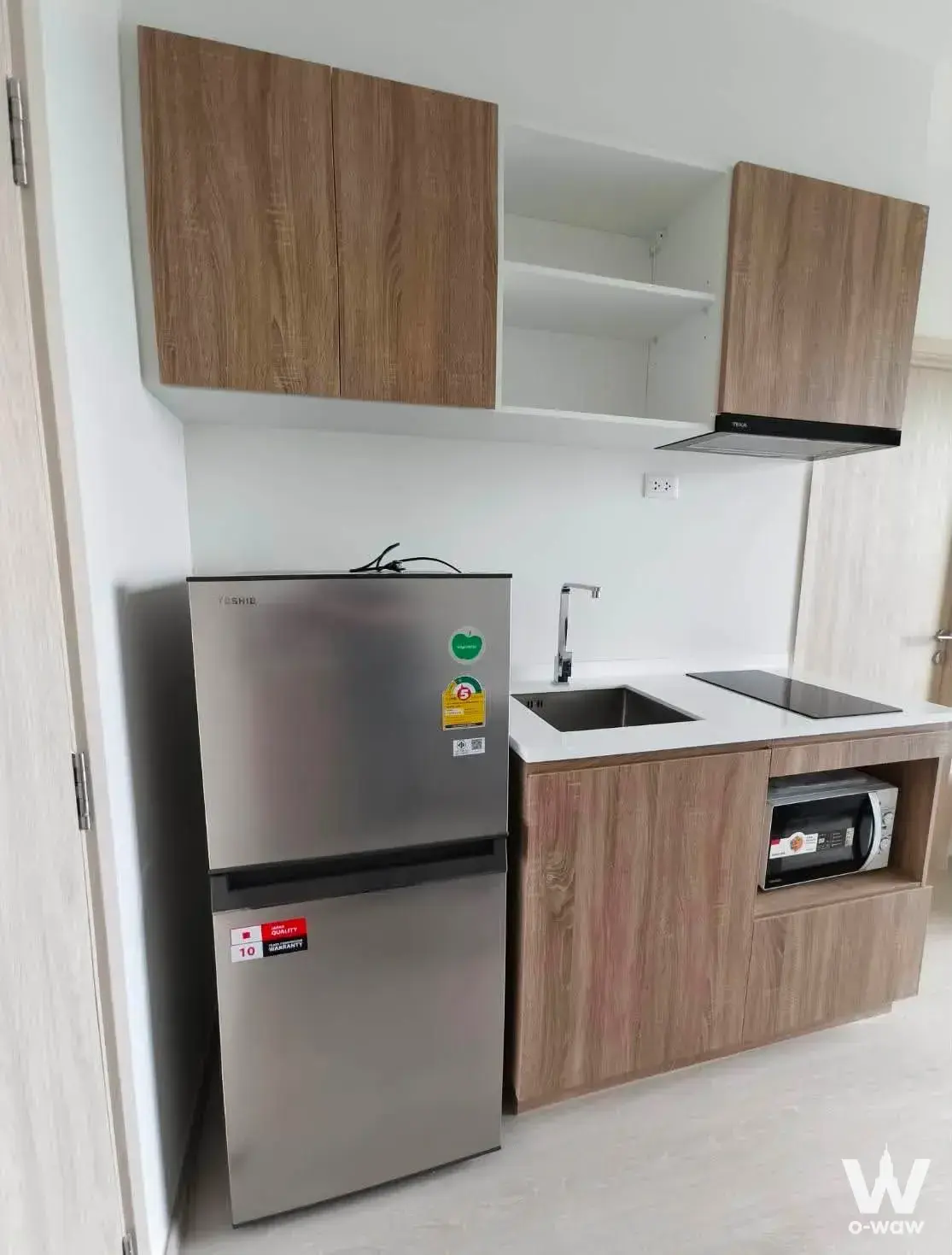 Compact kitchen with wood cabinets and stainless steel appliances in a NUE Noble Faichai Wang Lang condo