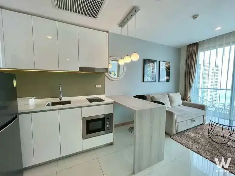 Open-plan kitchen and living area in a Jomtien condo with olive backsplash and city views