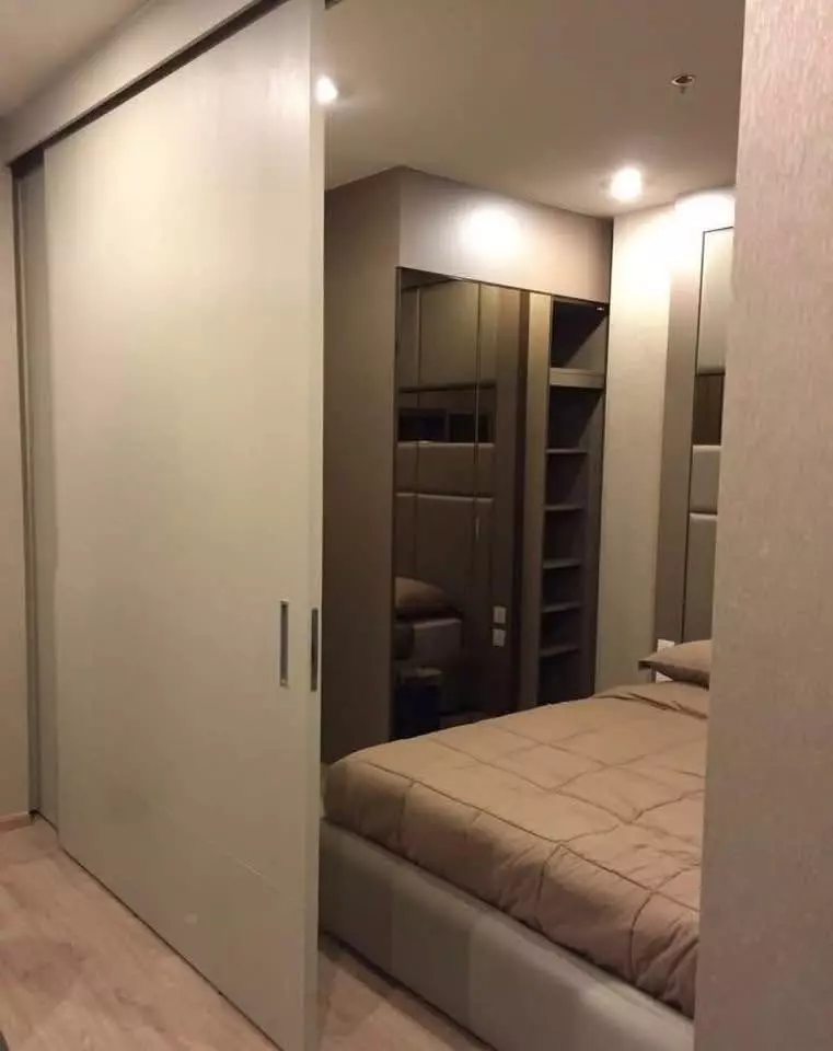 Bright bedroom in a 1-bed Ideo Q Chula-Samyan condo featuring mirrored built-in wardrobes and light wood flooring