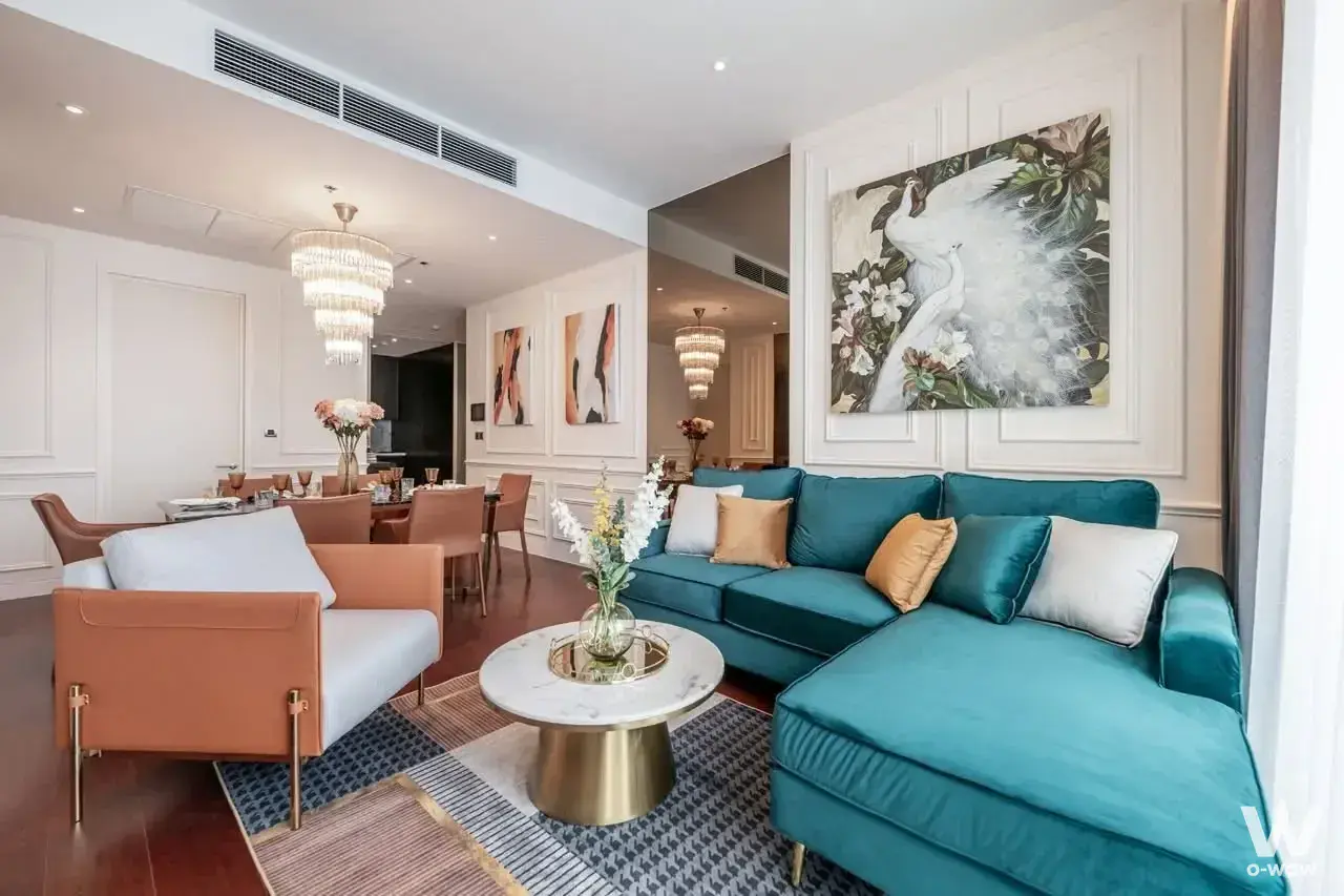 Luxury living area in a KHUN by YOO condo with teal velvet sofa marble table and crystal chandelier