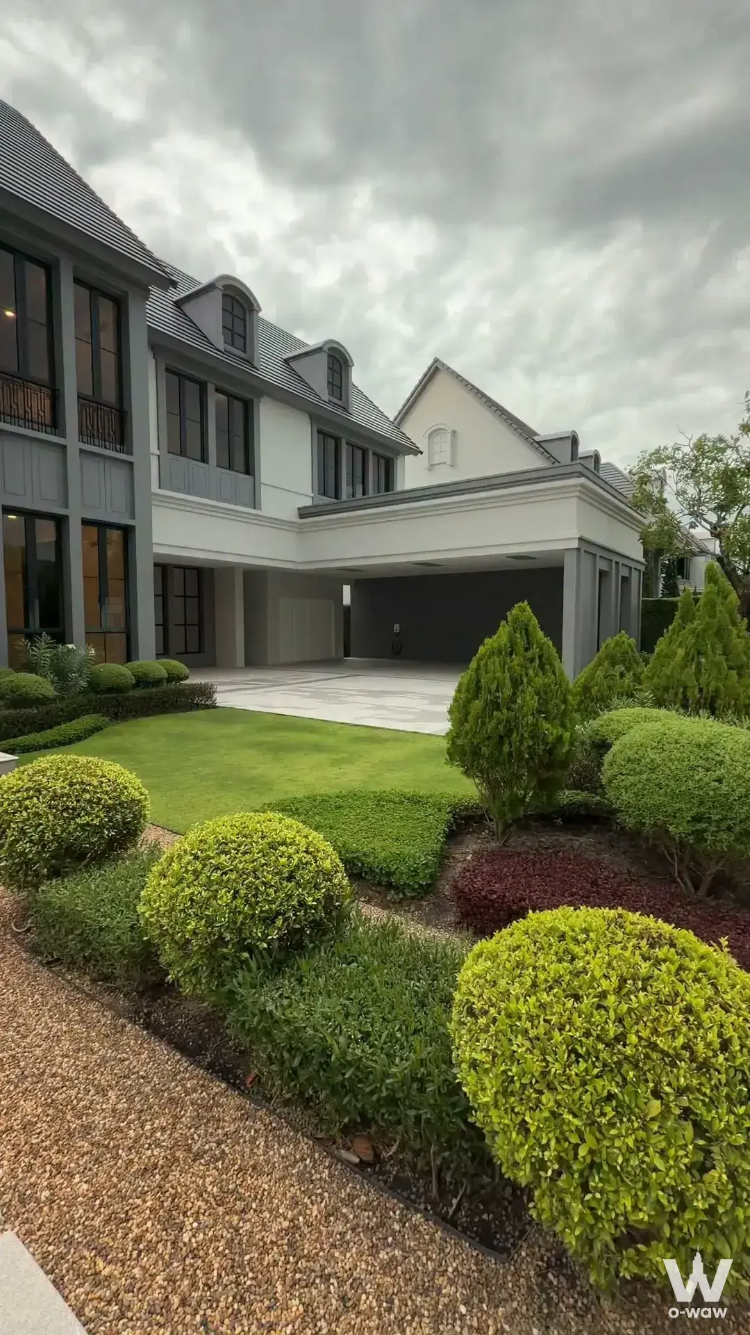5-bed house for sale in Narasiri Bangna with white stucco, grey shingles, and manicured green landscaping