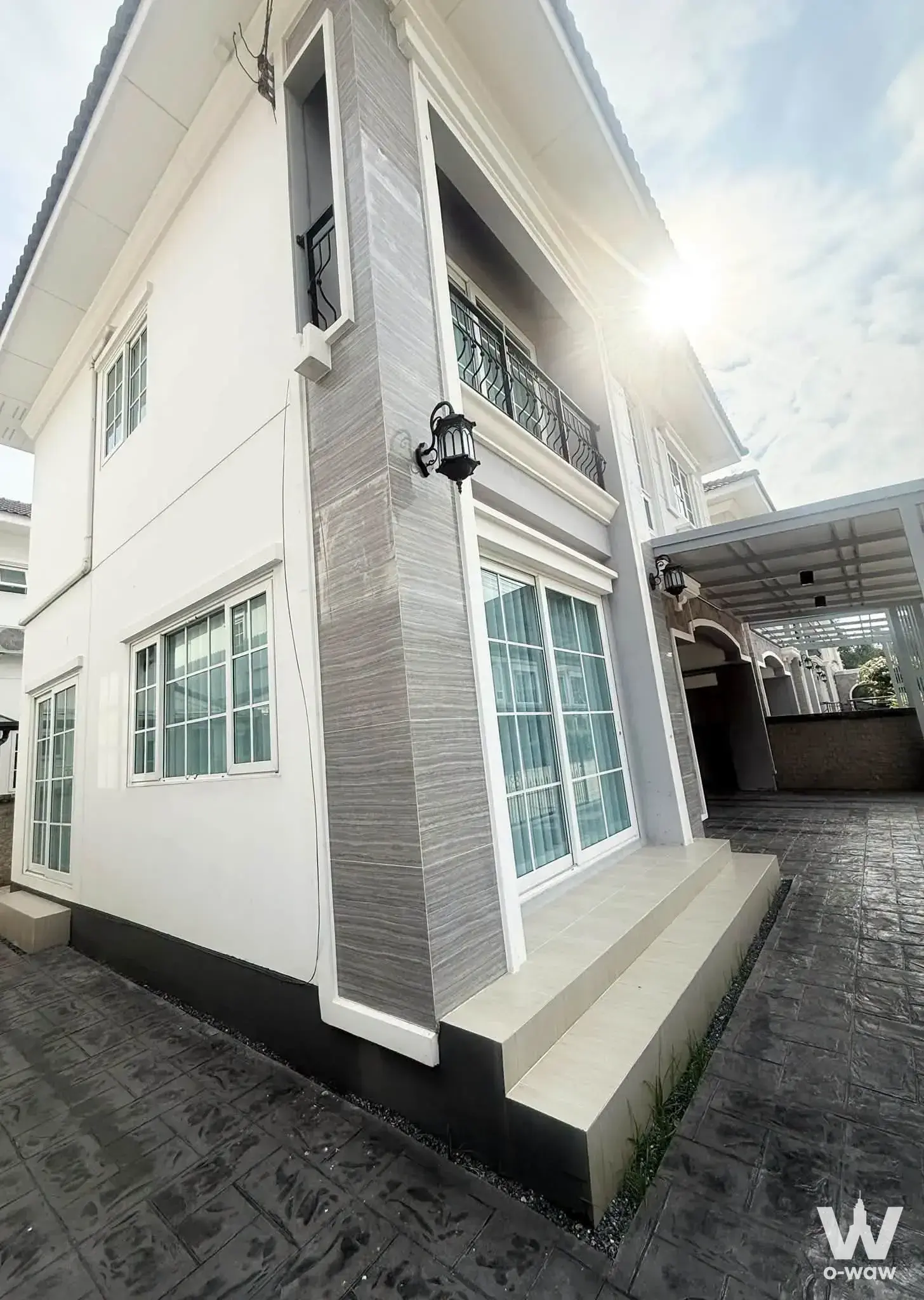 Golden Neo Sathorn 4-bed condo for rent has a two-story white exterior with stone column, balcony and sliding glass doors