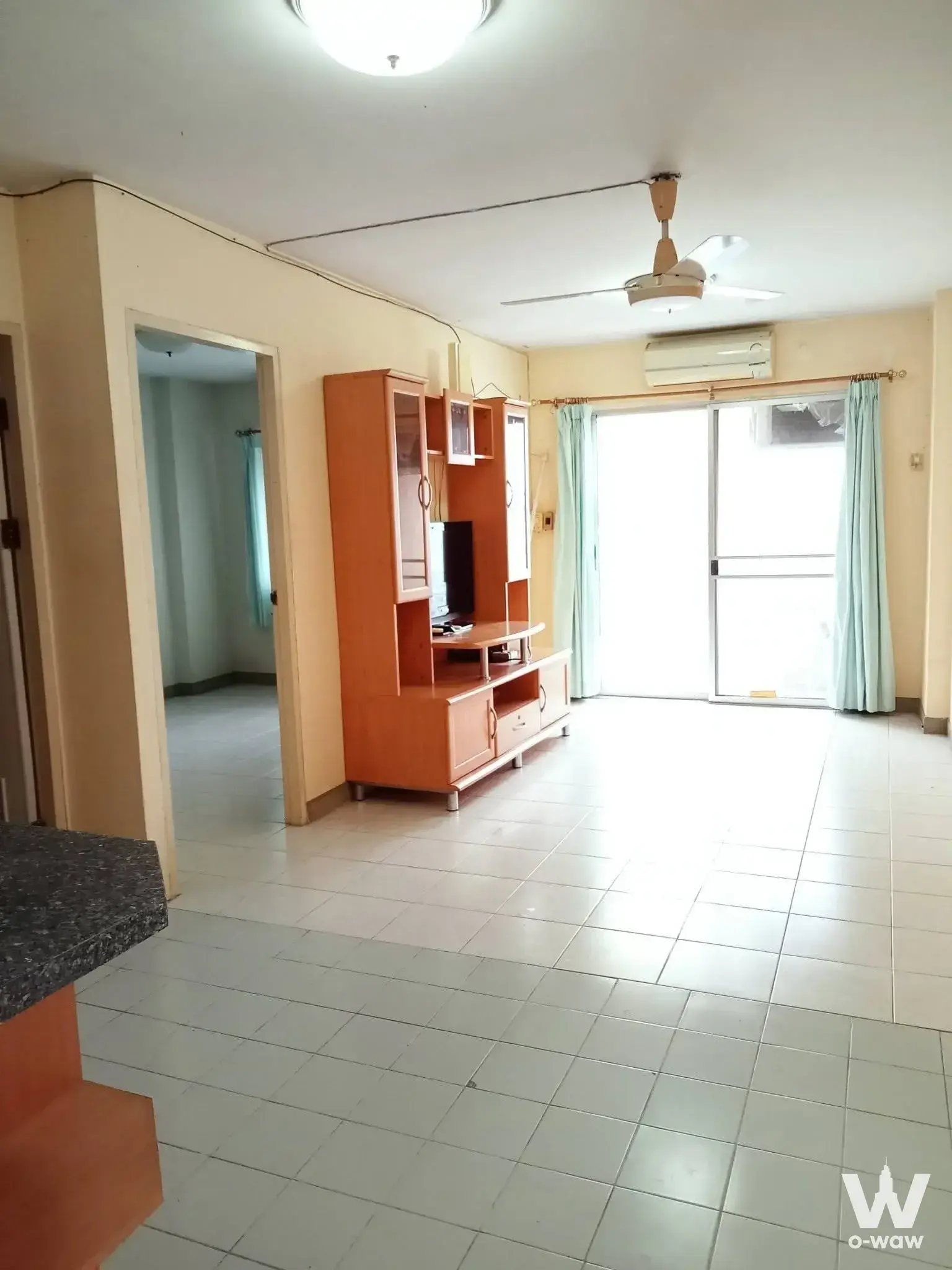 Empty living room in a 1-bed condo for sale at Tawanna Residence 2 with dated fixtures and honey-wood cabinet