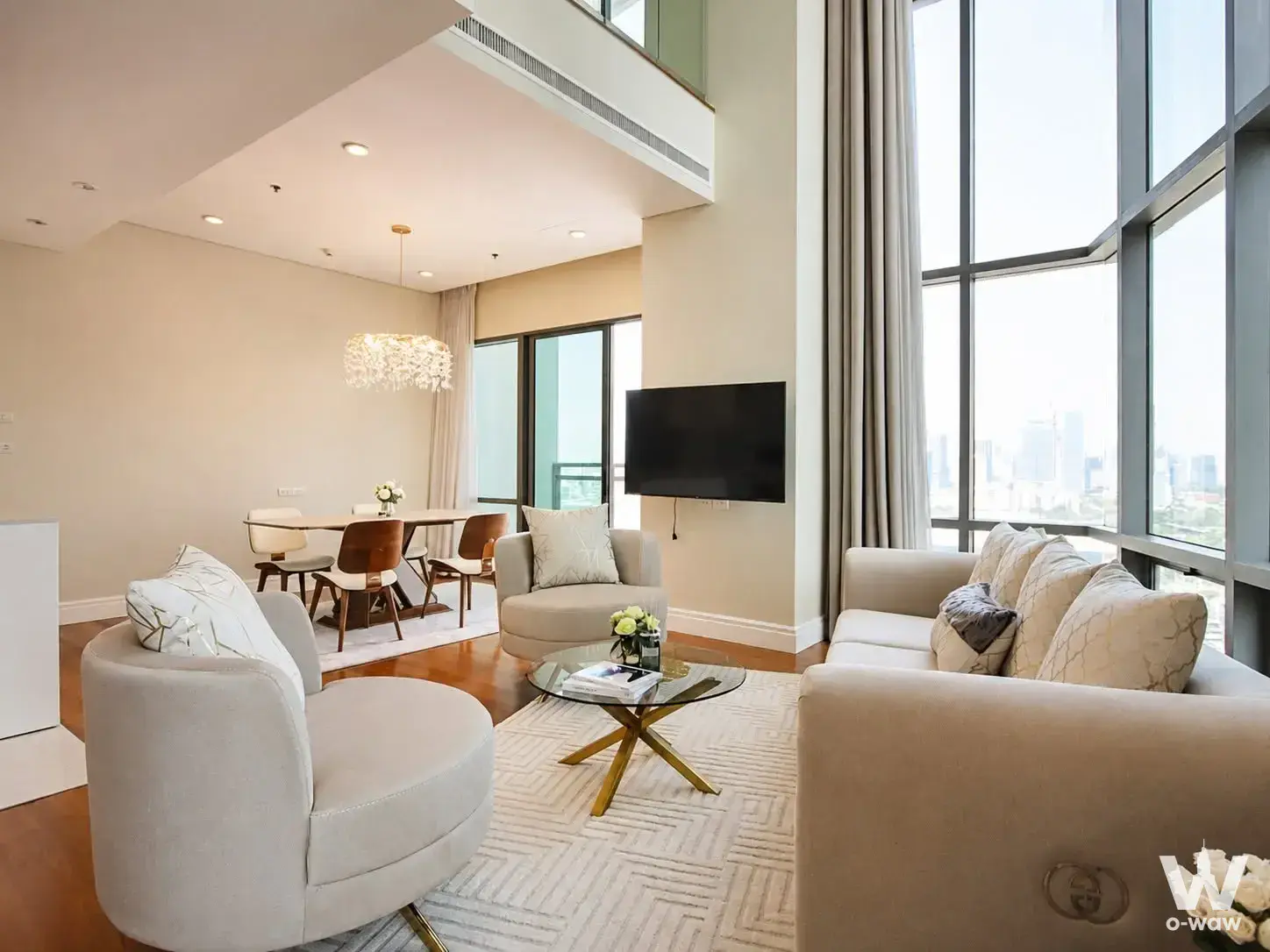 Open-plan living and dining area in a 3-bed Bright Sukhumvit 24 condo with hardwood floors and city skyline views