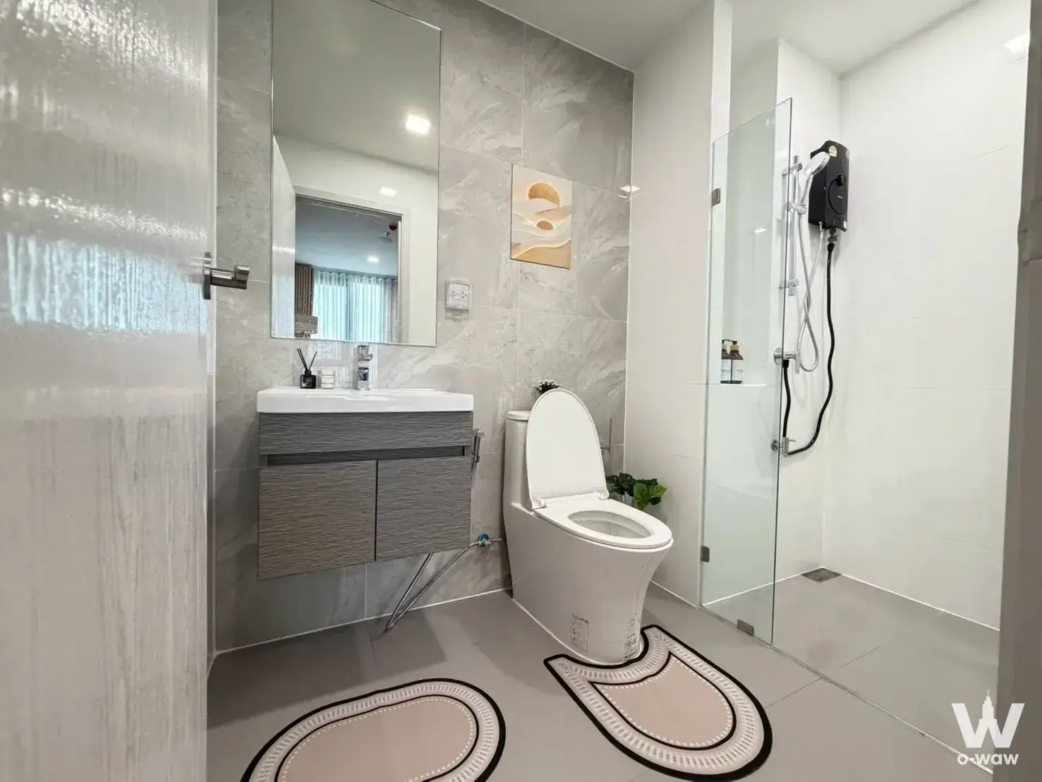 Modern bathroom in a 2-bed condo for rent in Modiz Rhyme Ramkhamhaeng with grey marble tiles, floating vanity, and glass
