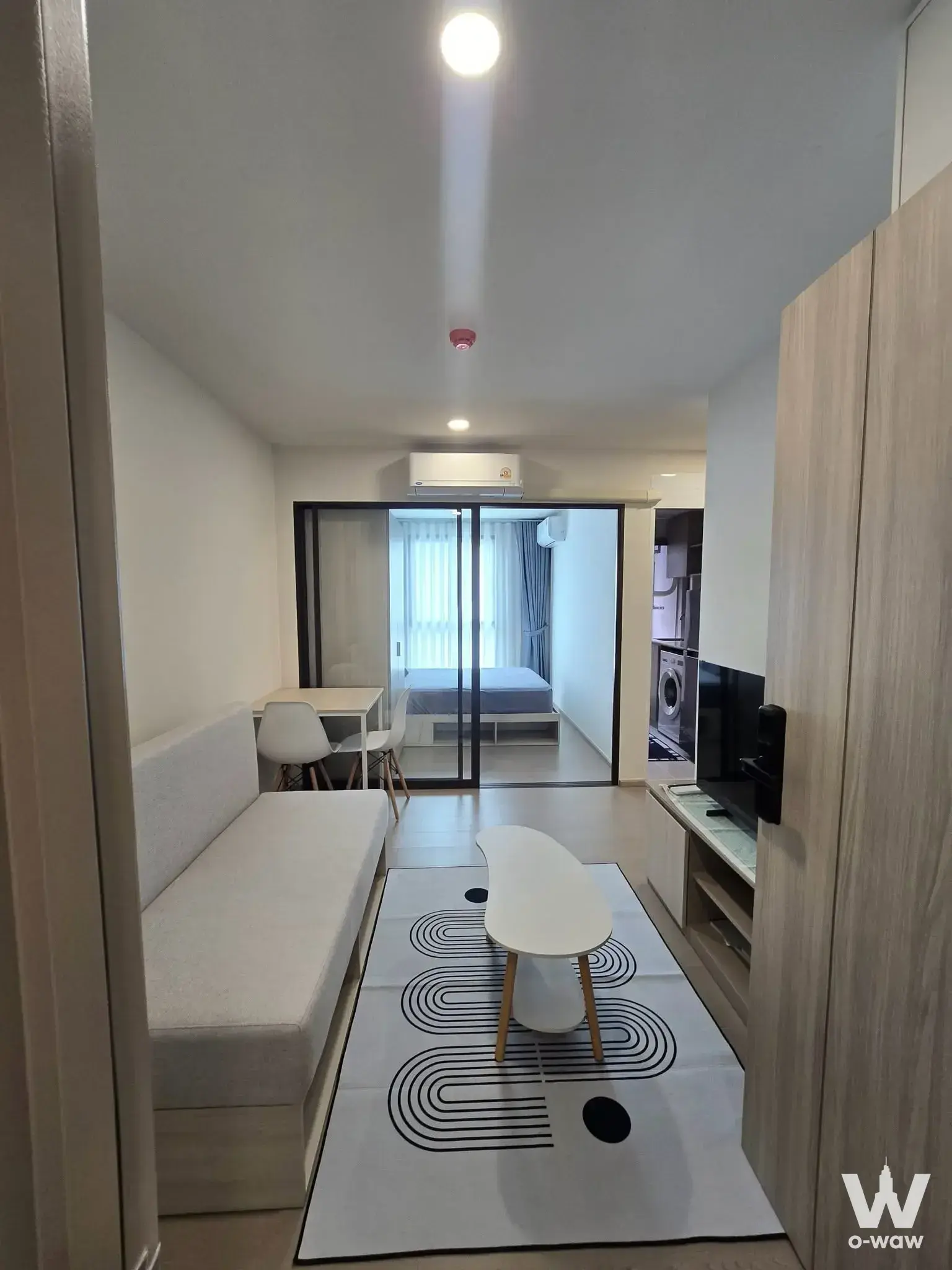 1-bed condo for rent in GOOD DAY สุขุมวิท 93 living room with built-in bench, dining set, and glass partition