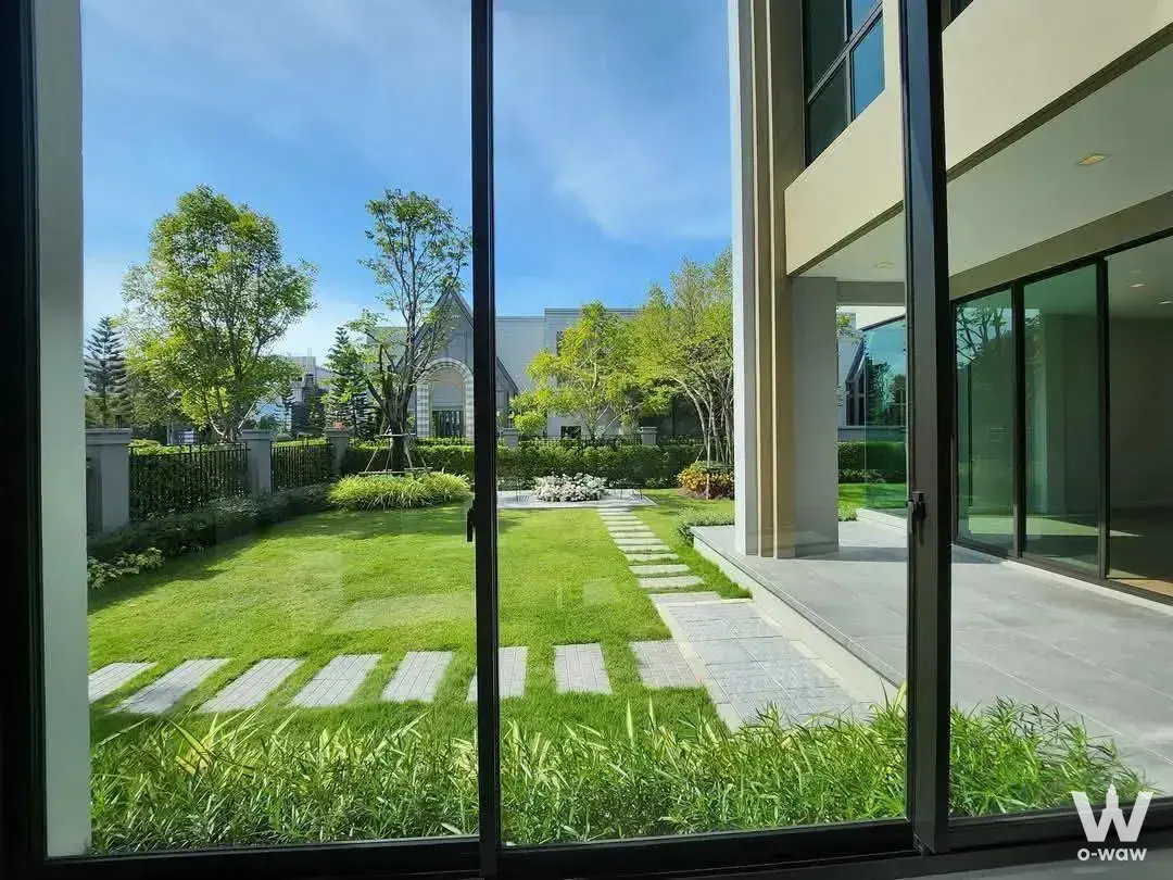 Garden courtyard with stone pavers and manicured lawn viewed through sliding doors in 0-bed house for sale at Grand Bangkok
