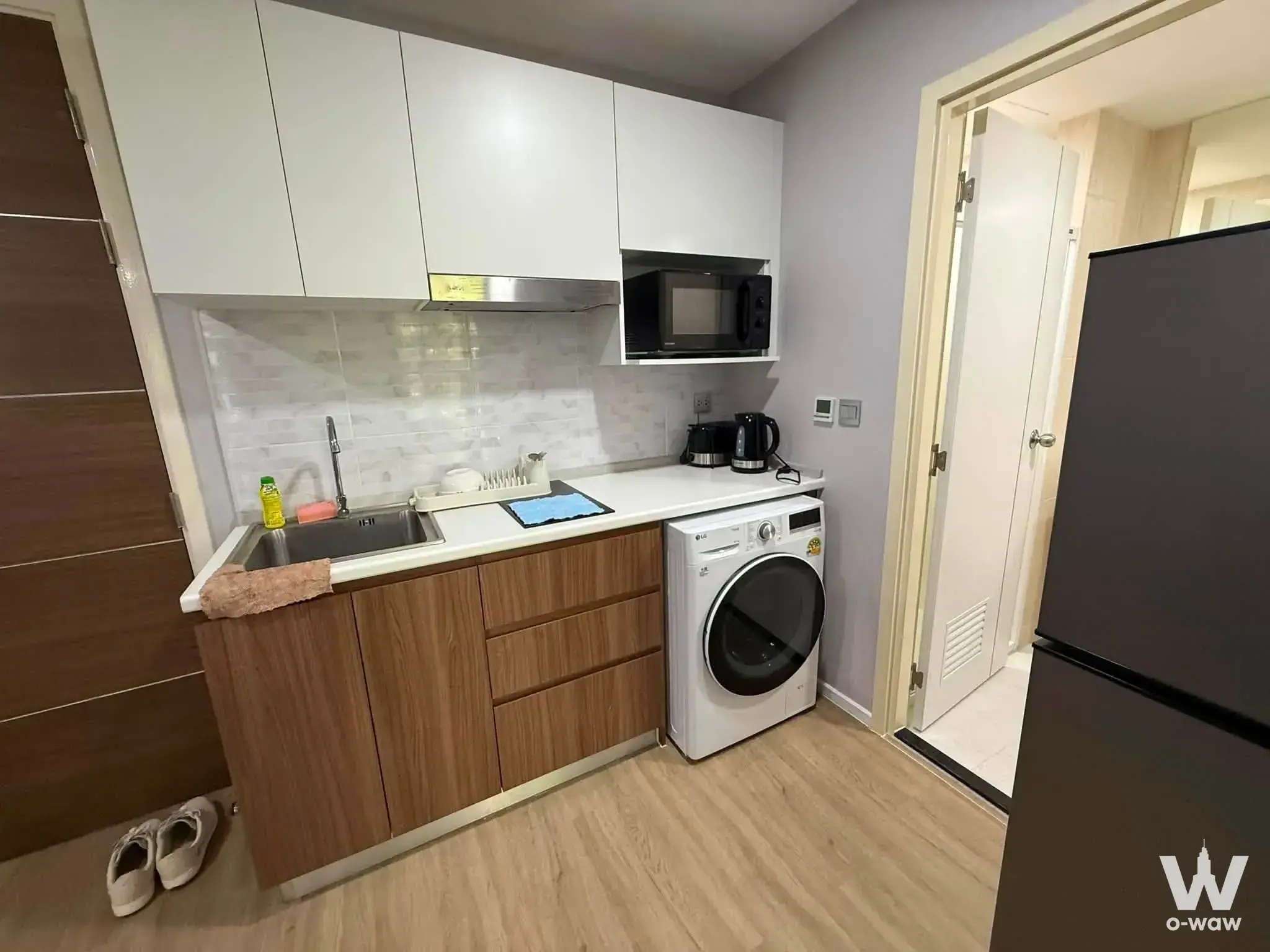 Compact kitchenette with white cabinets and a washing machine in this 2-bed Atmoz Ladprao 71 condo