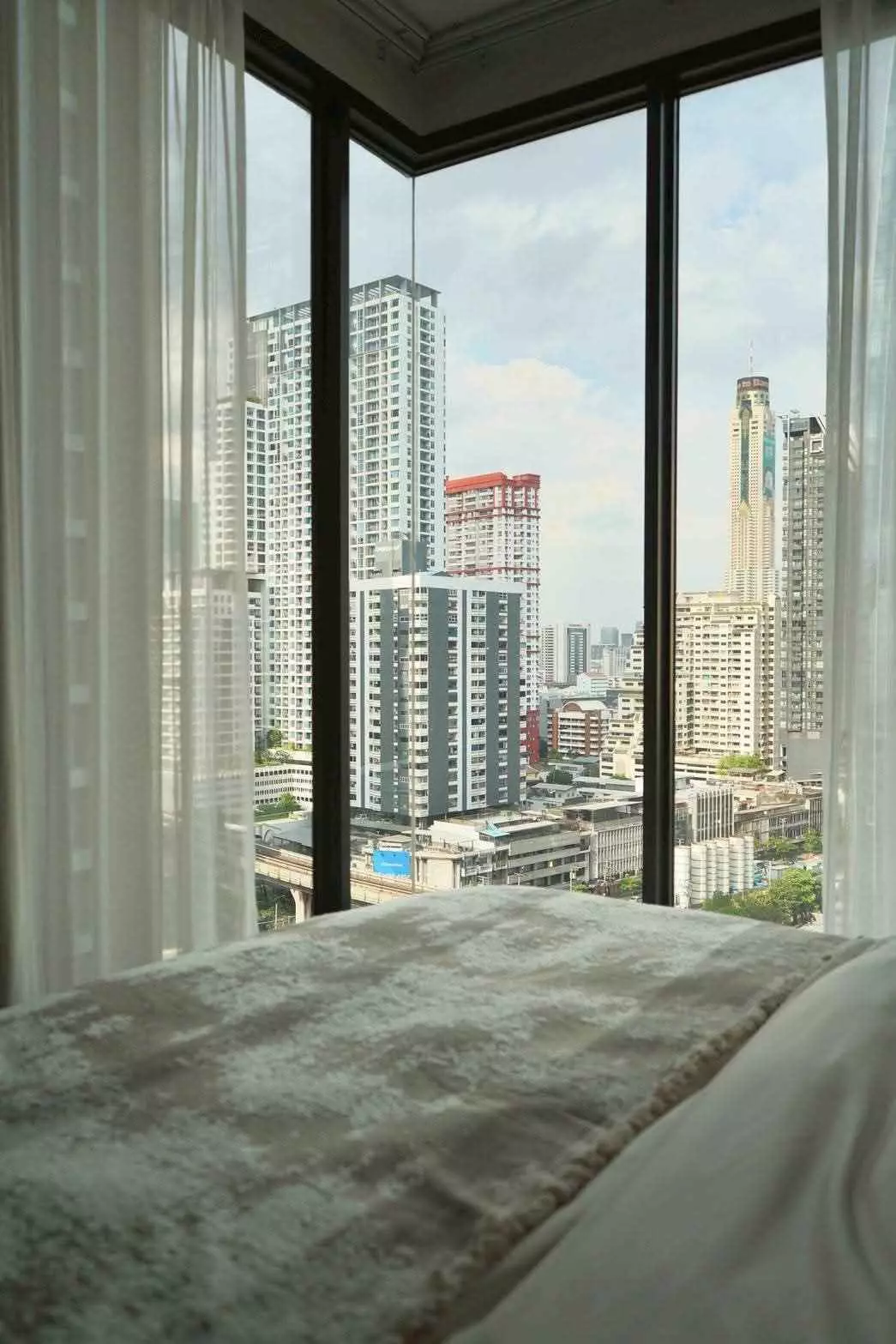 Bedroom with floor-to-ceiling windows and city skyline view at The Address Siam-Ratchathewi