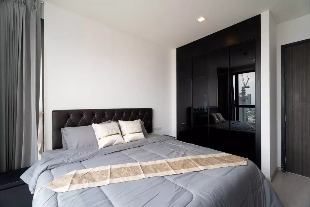 2-bed condo for sale in RHYTHM Sukhumvit 44/1 master bedroom with dark tufted headboard and black high-gloss wardrobe doors