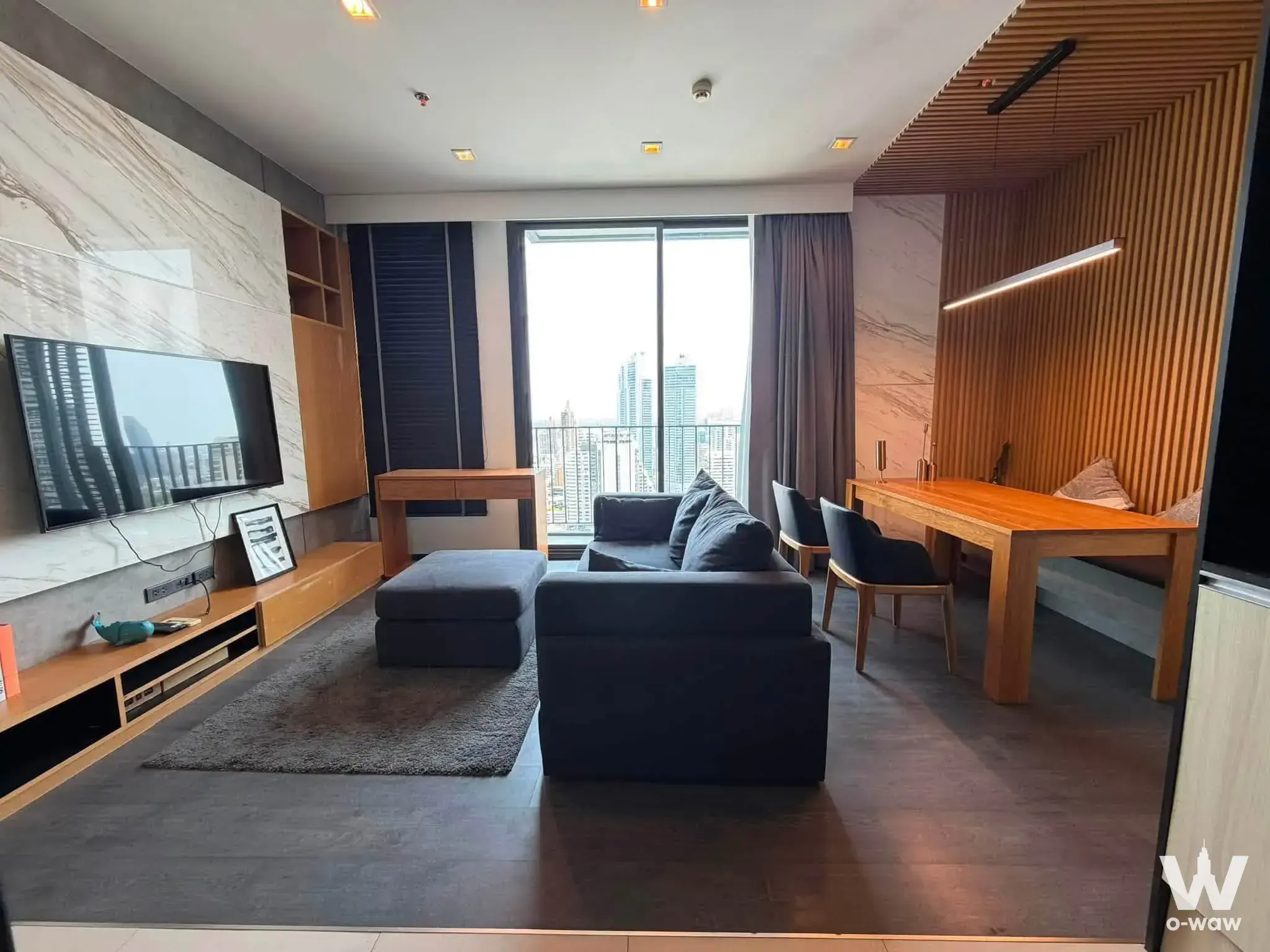 Open-plan living and dining area in a 2-bed condo at The Edge Sukhumvit 23 with marble wall and city view