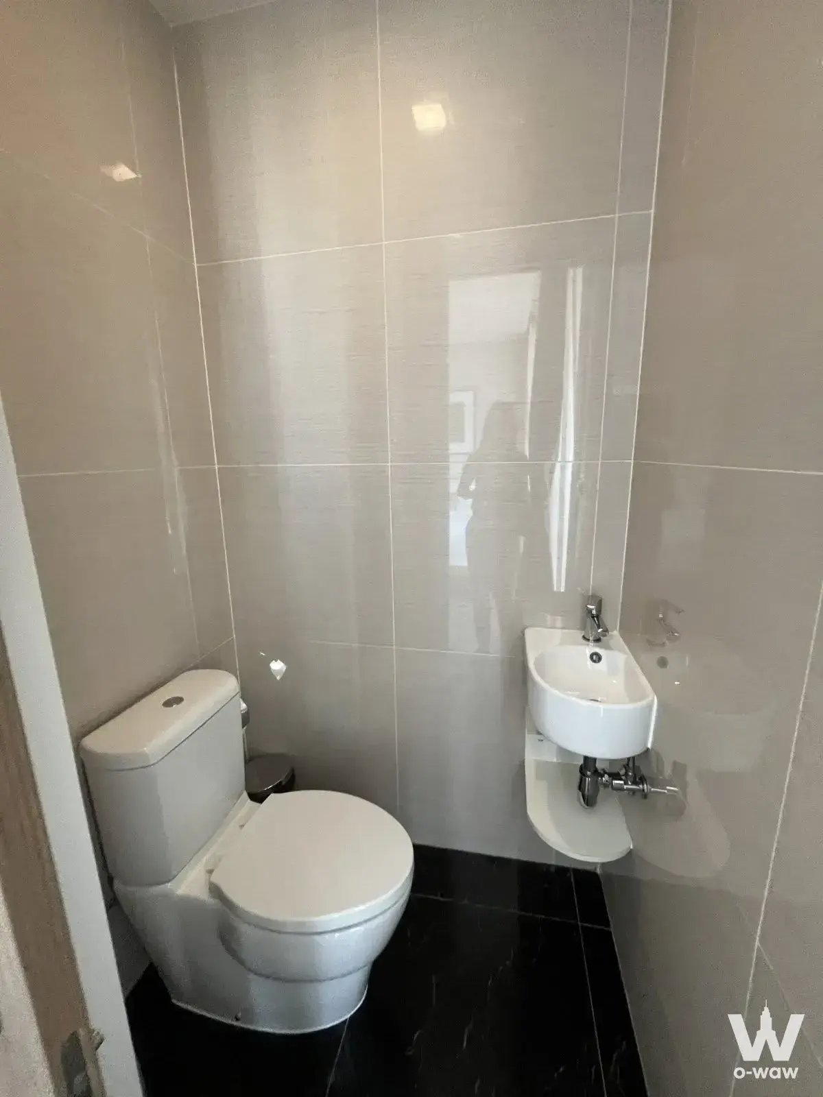 Compact bathroom in a Park Origin Phrom Phong condo with glossy grey tiles and black marble-look floors