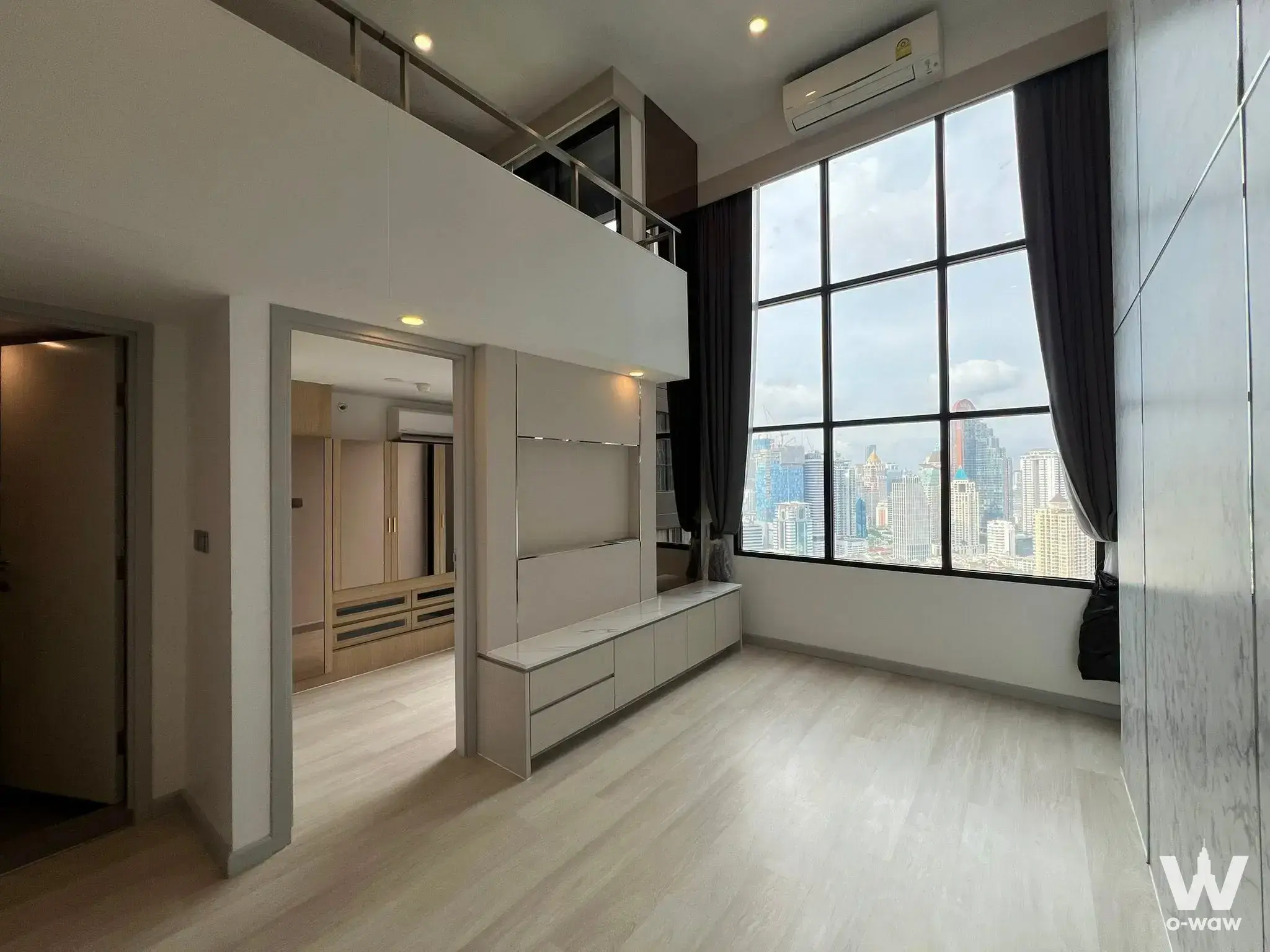 Duplex loft living area featuring light wood floors and high-floor city views in a 1-bed condo for sale at KnightsBridge