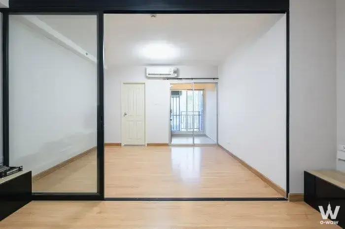 Empty 1-bed condo room at Supalai Veranda Ratchawipha-Pracha Chuen featuring oak floors and glass partition doors