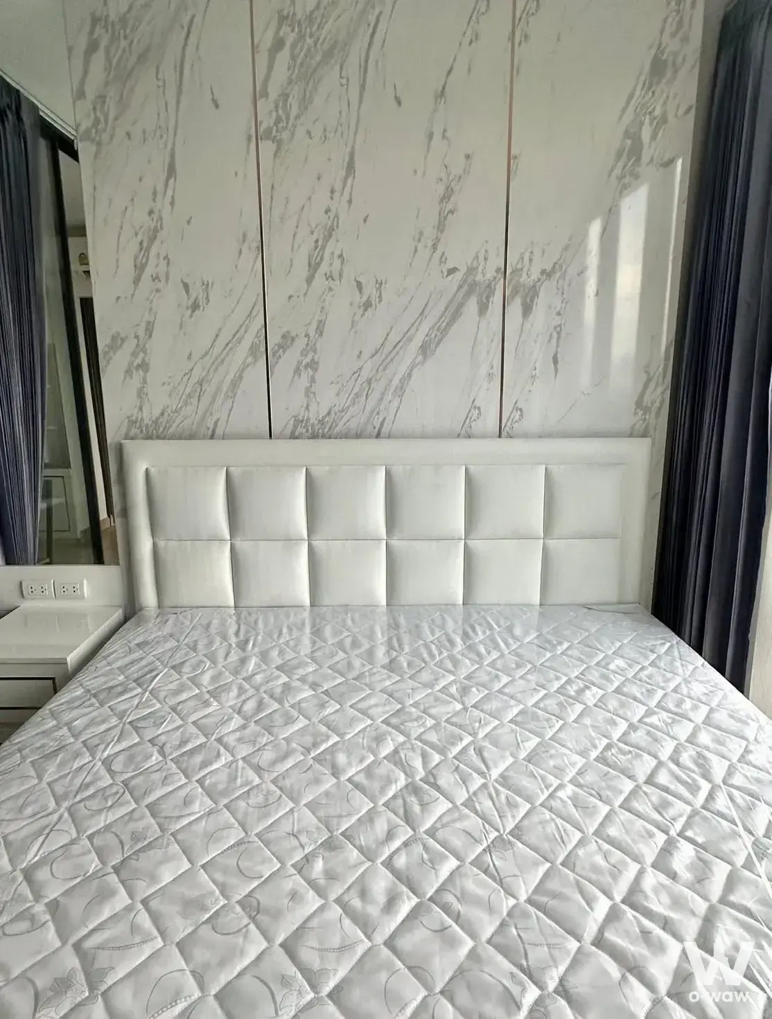 Bedroom in Supalai Prime Rama 9 featuring white tufted headboard and marble-look feature wall