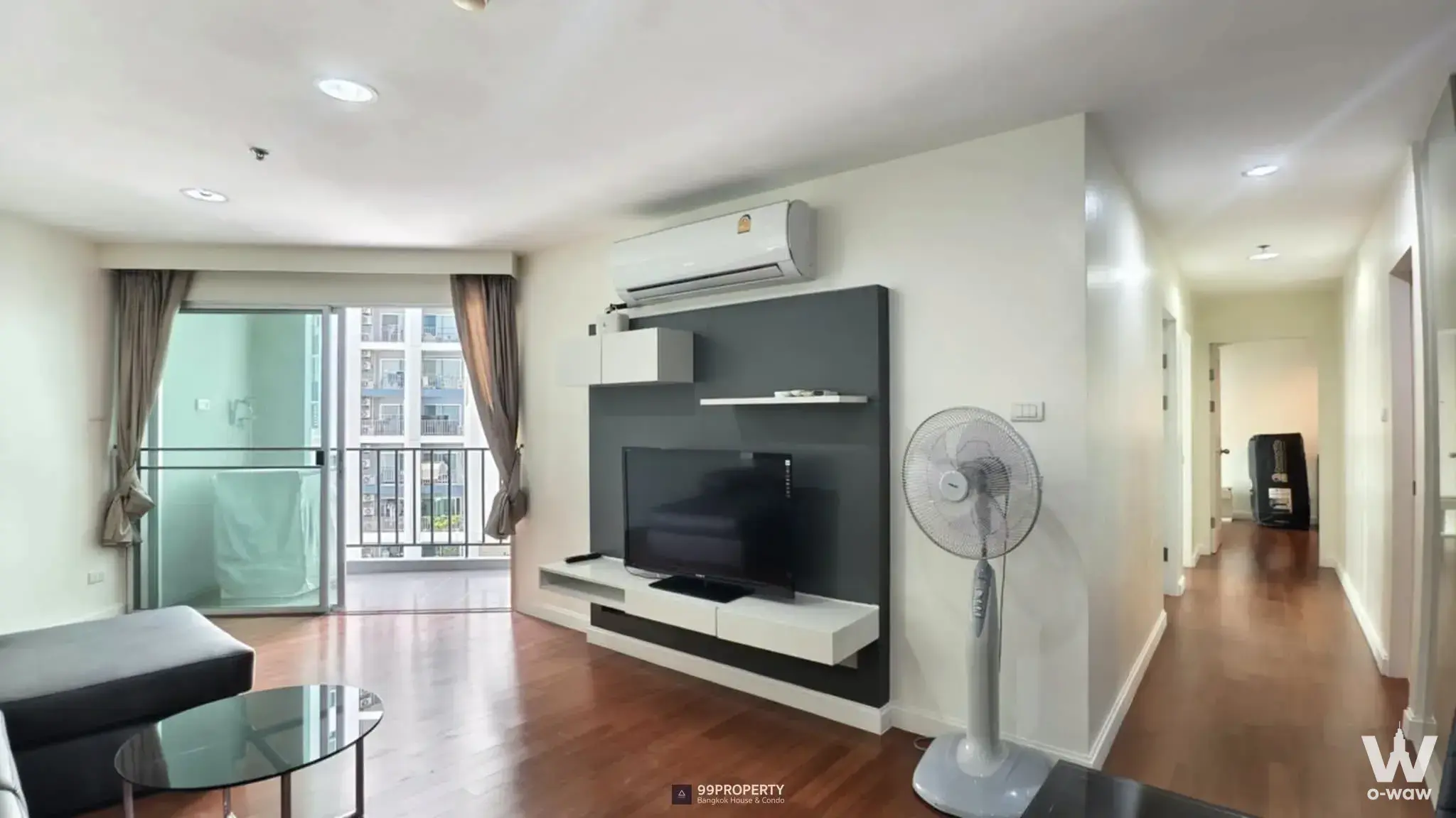 Furnished living room in Belle Grand Rama 9 condo featuring grey sofa, TV console, and balcony access