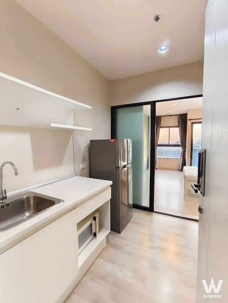 Kitchenette in a Plum Condo unit featuring white cabinets and stainless sink