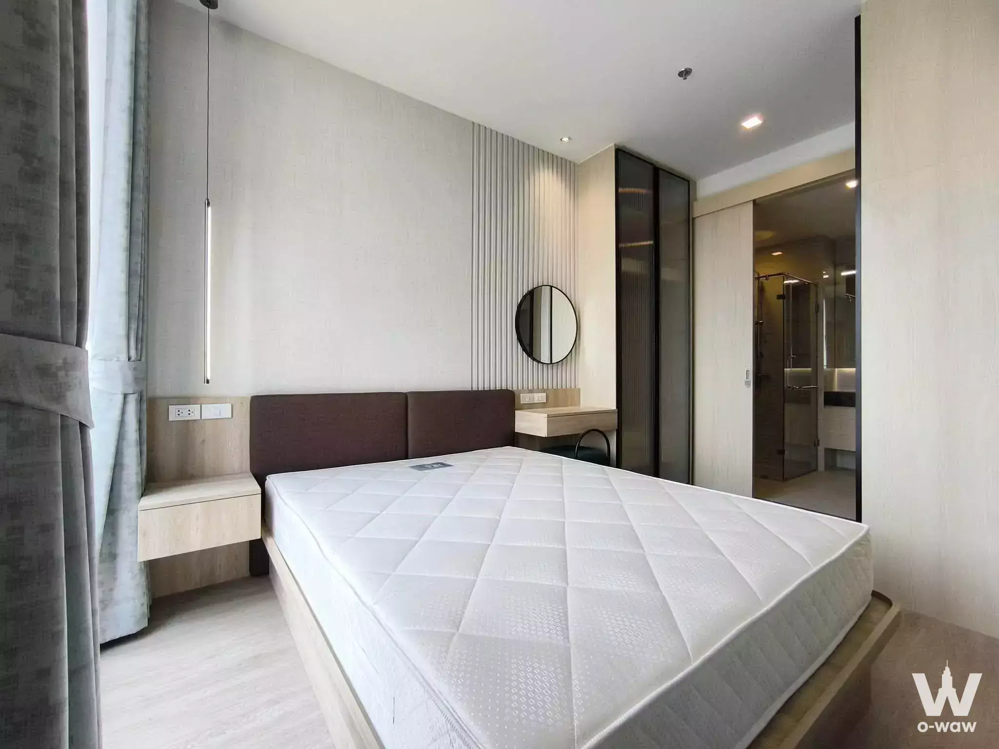 Minimalist bedroom in Noble State 39 with a dark headboard, floating nightstand, and view into the en-suite bathroom