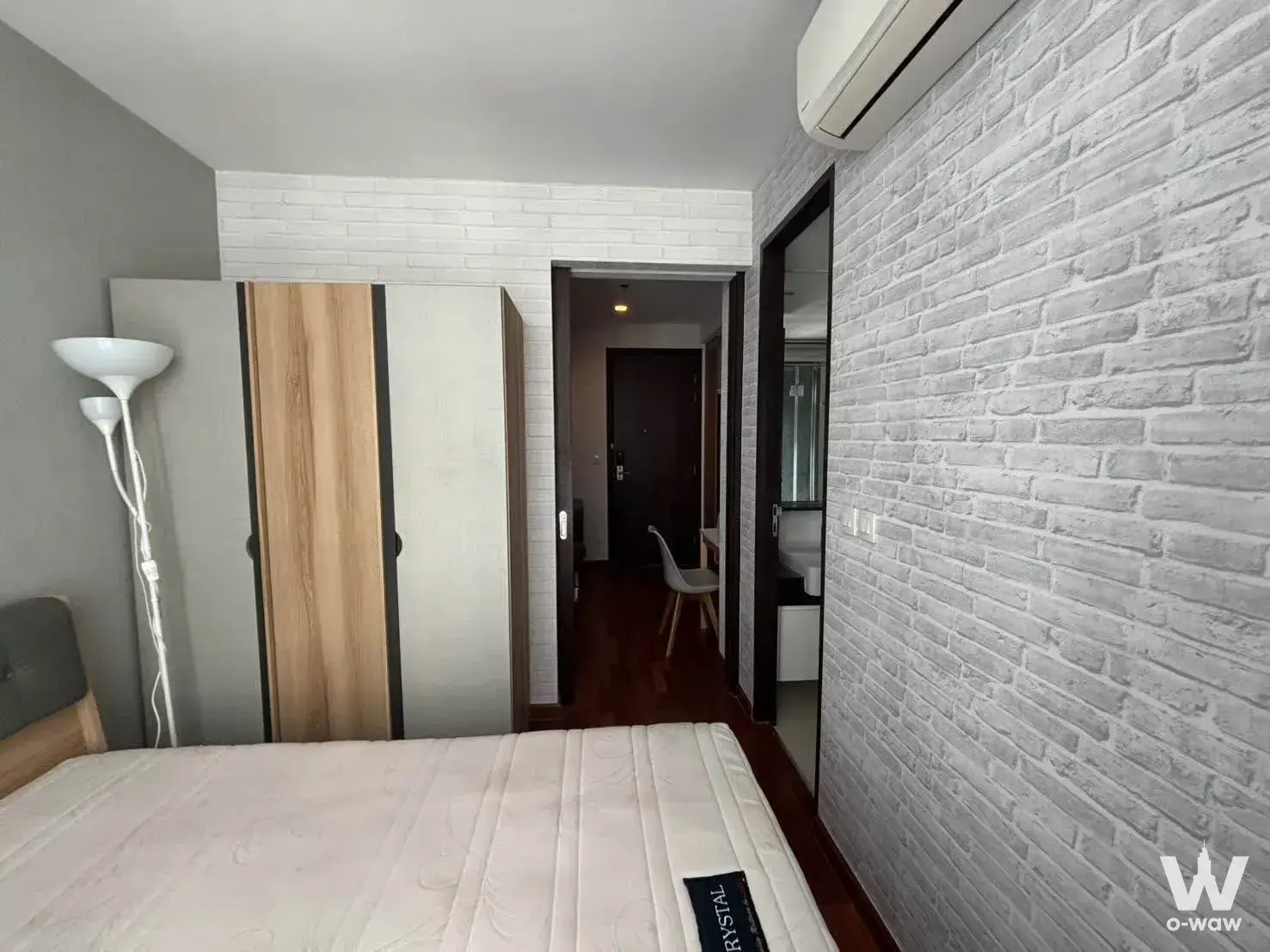 Bedroom in WISH Signature Midtown Siam featuring a grey upholstered headboard, faux brick accent wall, and sliding wardrobe