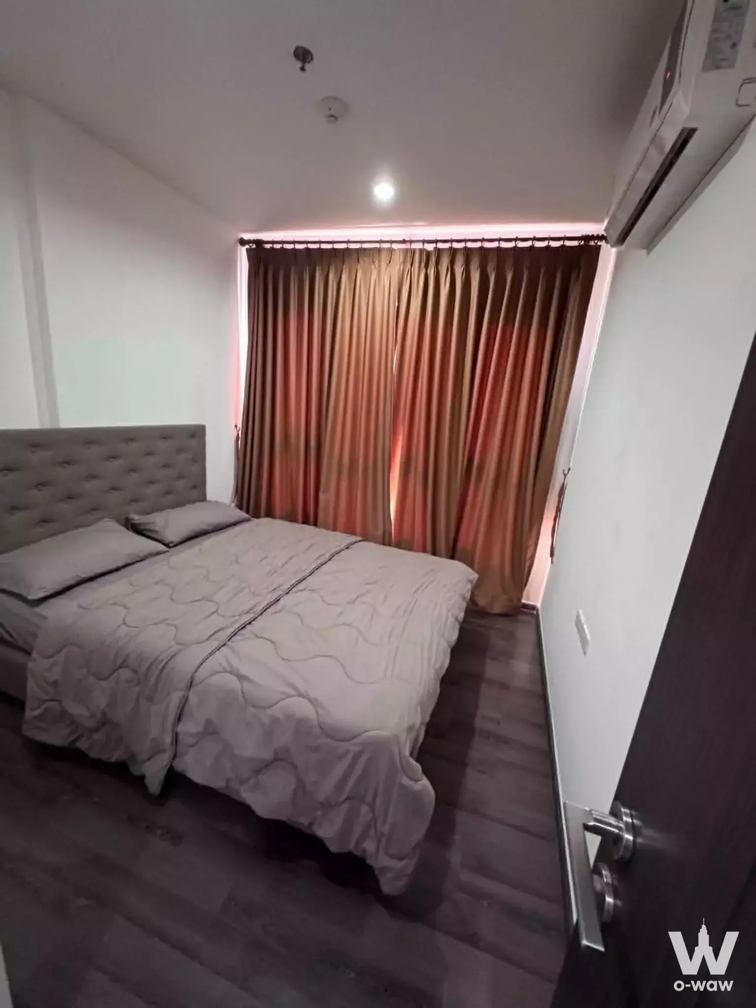 Bedroom in The Base Park East condo featuring a queen bed and bronze drapes
