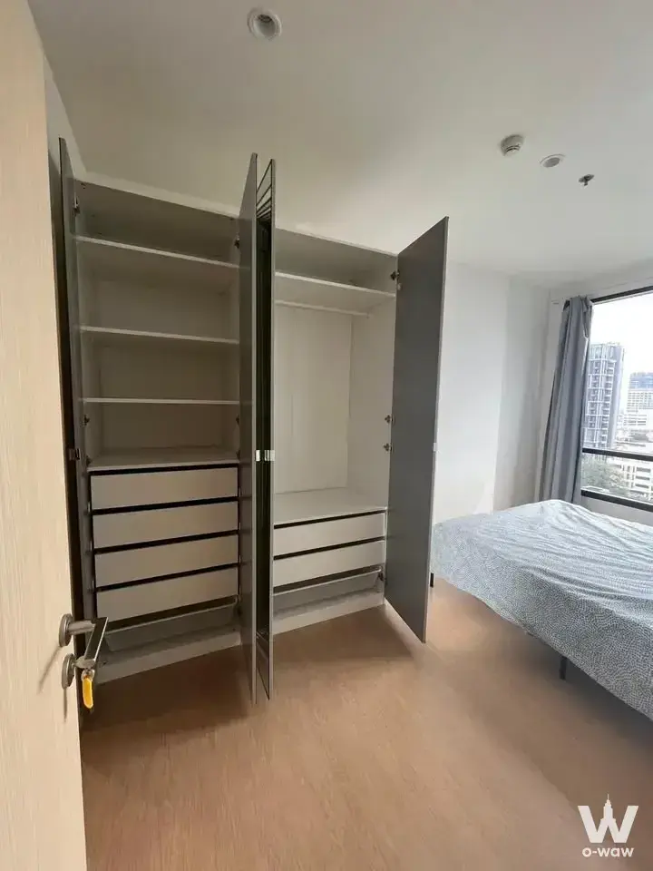 Bedroom wardrobe with open shelves and drawers overlooking city skyline in MARU Ekkamai 2 condo