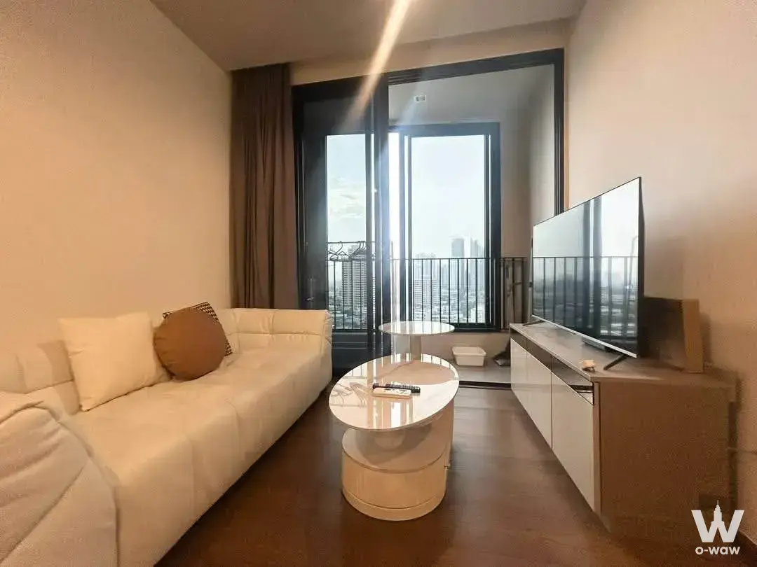 Cream leather sofa and TV console in the living room of a 1-bed condo for rent at Ideo Q Sukhumvit 36 with sliding glass