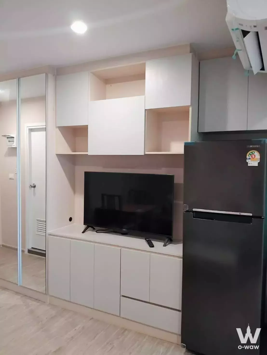 Regent Home Bangna 1-bed condo living room with white cabinetry, TV, and fridge