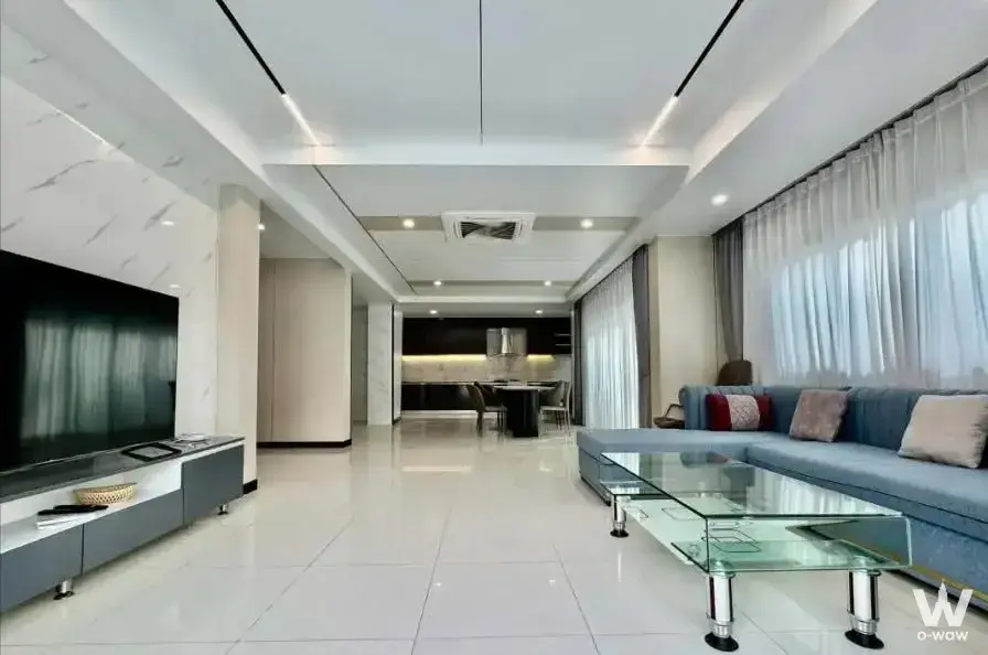 4-bed condo for rent in The Lakes featuring blue sectional sofa and marble feature wall