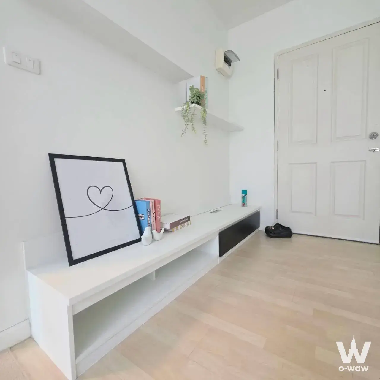 Minimalist entryway in Dcondo Ramindra condo with white media console, art print, and green vines