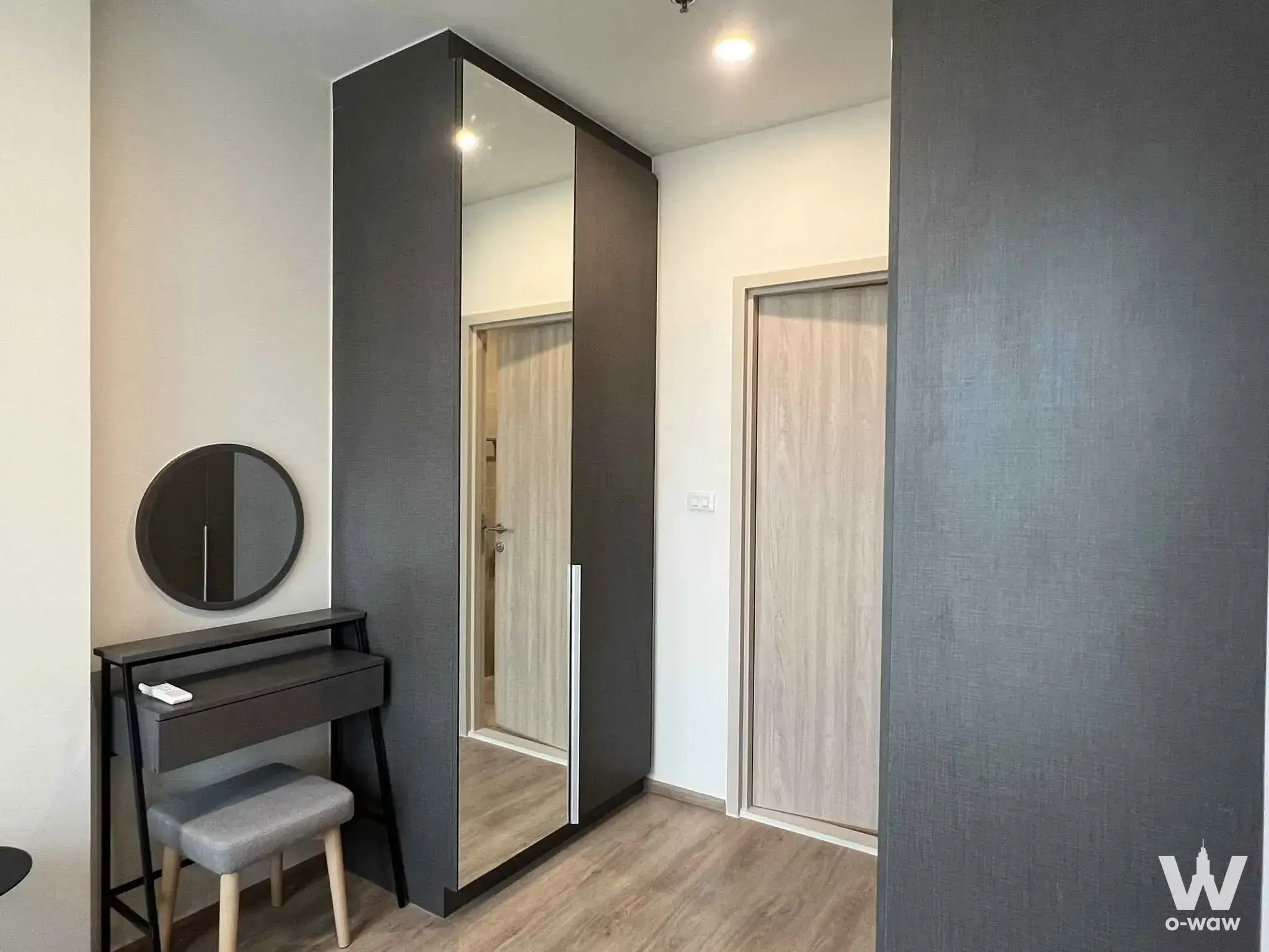 This bedroom entryway has a grey vanity desk and wardrobe in a 3-bed condo for rent in Nue District R9