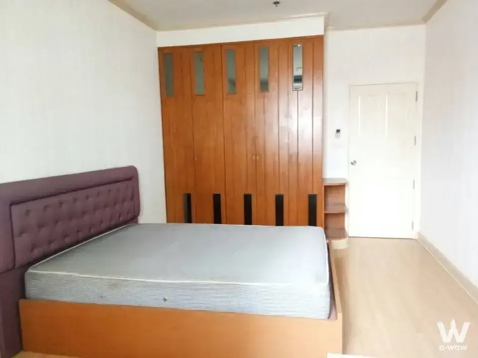 The bedroom in a 2-bed Waterford Park condo for rent has a purple tufted headboard and built-in wooden wardrobe