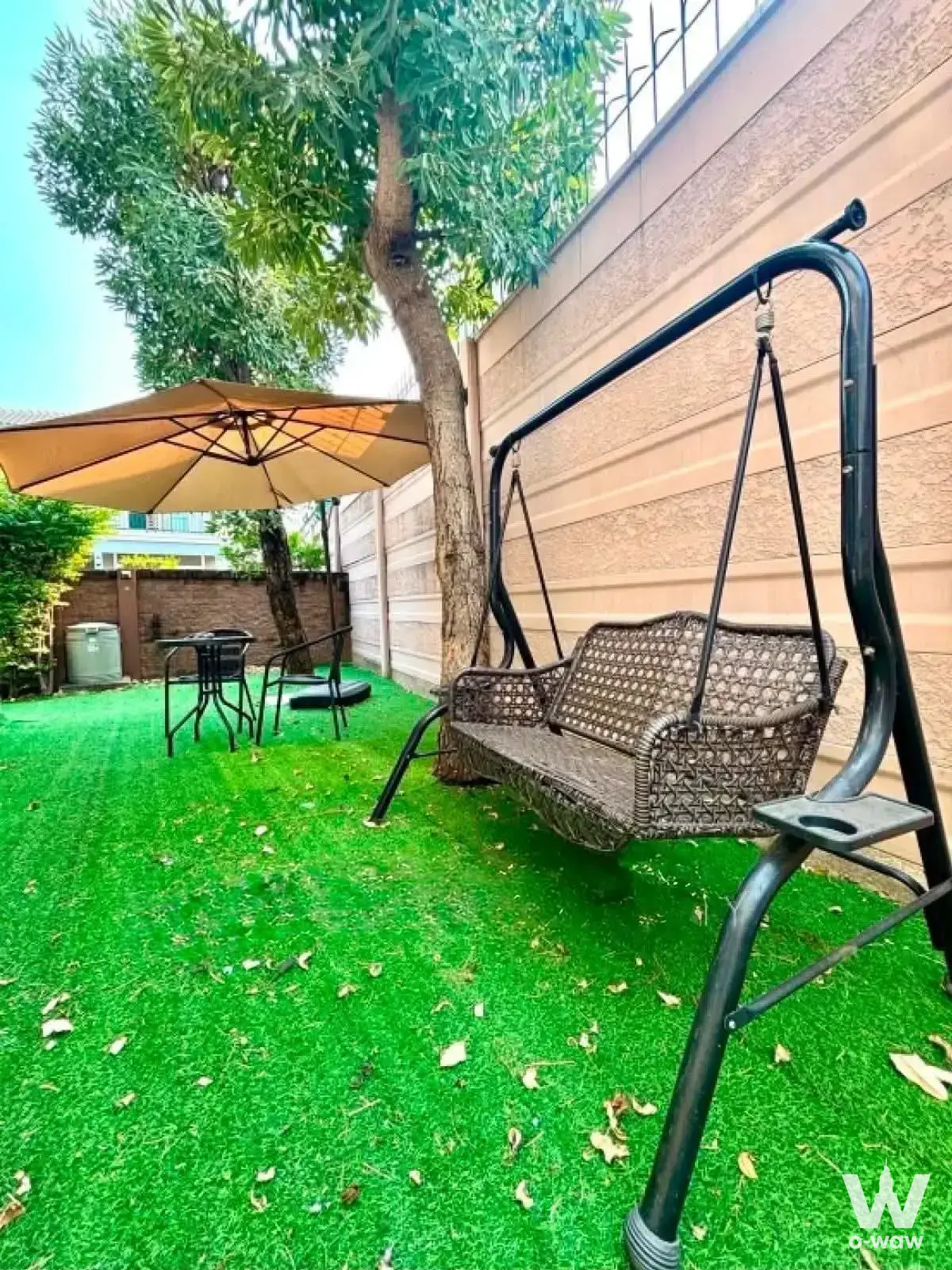 Private backyard garden in Passorn Prestige Luxe with wicker swing and mature tree canopy