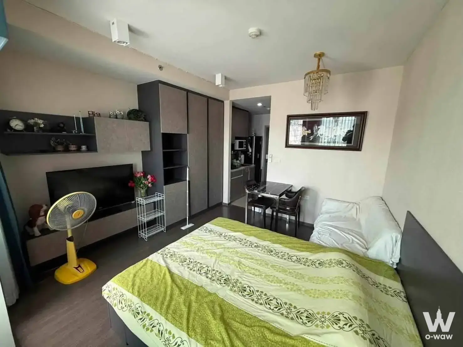 Ideo Phaholyothin furnished studio with grey media console, glass dining table, and gold crystal chandelier